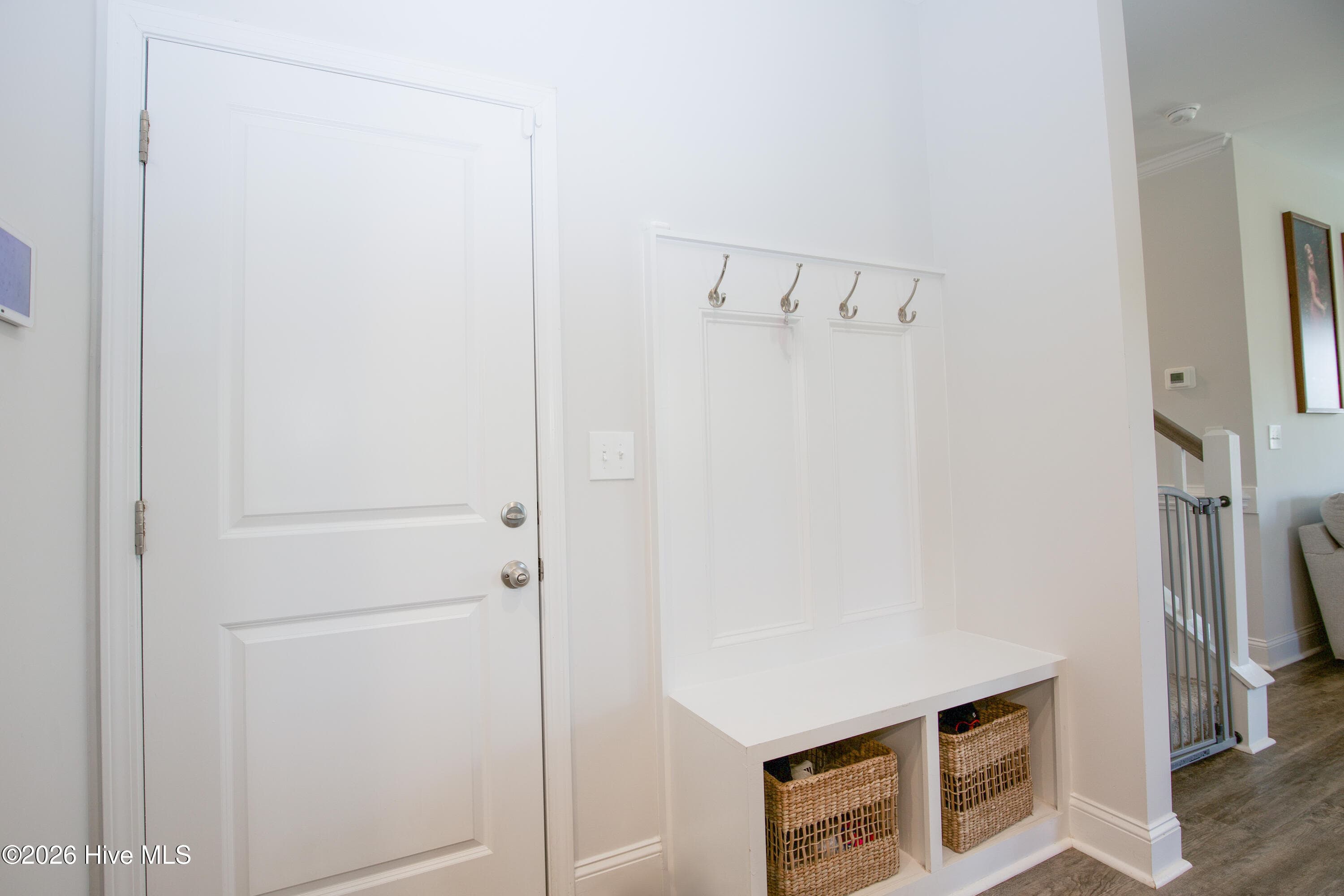 The built-in drop zone combines a bench, cubbies below, and four coat hooks in one compact spot near the kitchen. It is a practical feature for everyday comings and goings, giving backpacks, jackets, and shoes a place to land. Nearby doors lead to the pantry and the attached two-car garage, keeping storage close at hand. - 221 Vega Lane, Linden, NC 28356