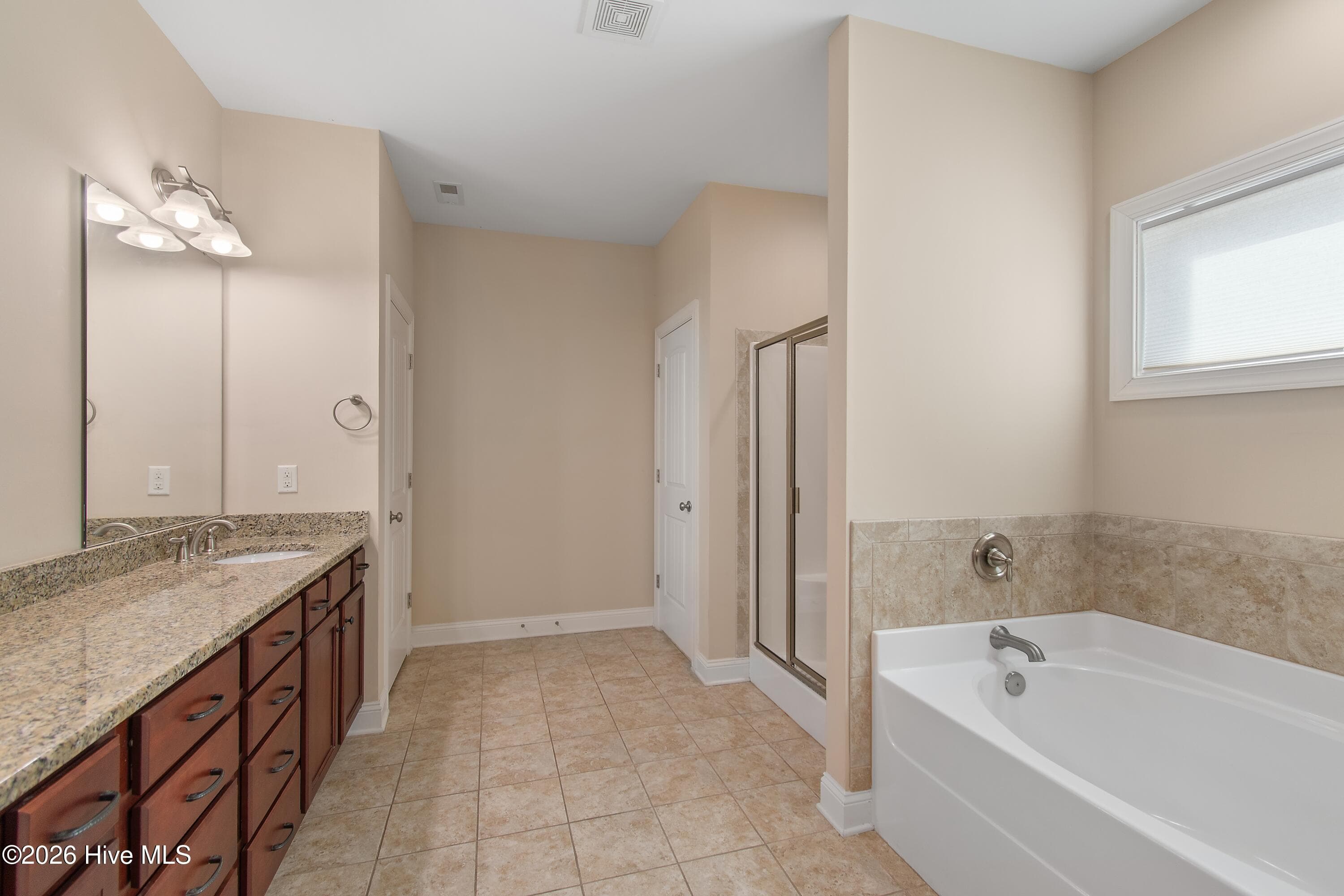 Primary en suite bathroom with dual sinks, bath tub and shower. - 1674 Back Bay Drive SW, Shallotte, NC 28470