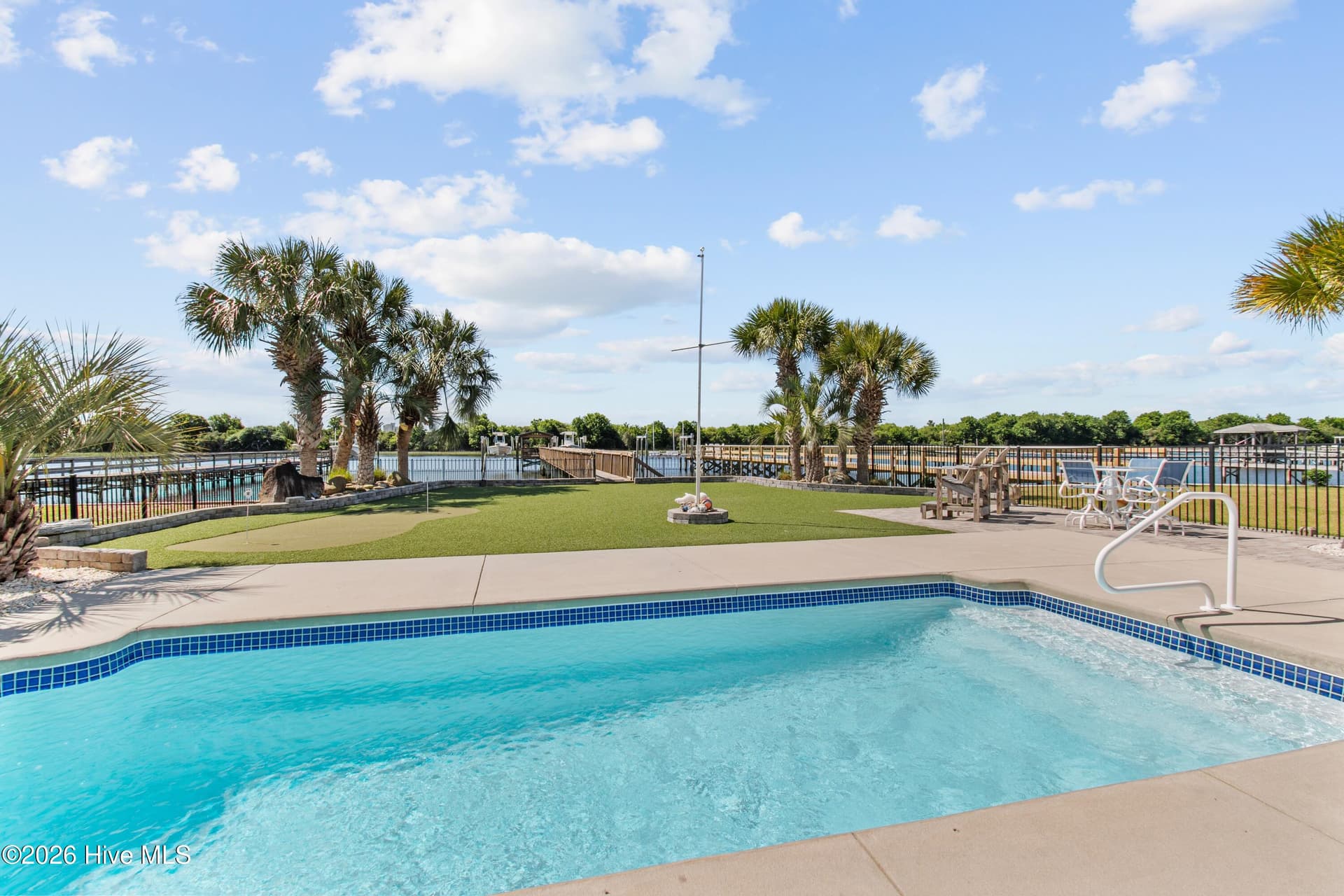 Large pool with coastal landscaping and fenced backyard. - 2024 Camelot Drive SW, Ocean Isle Beach, NC 28469