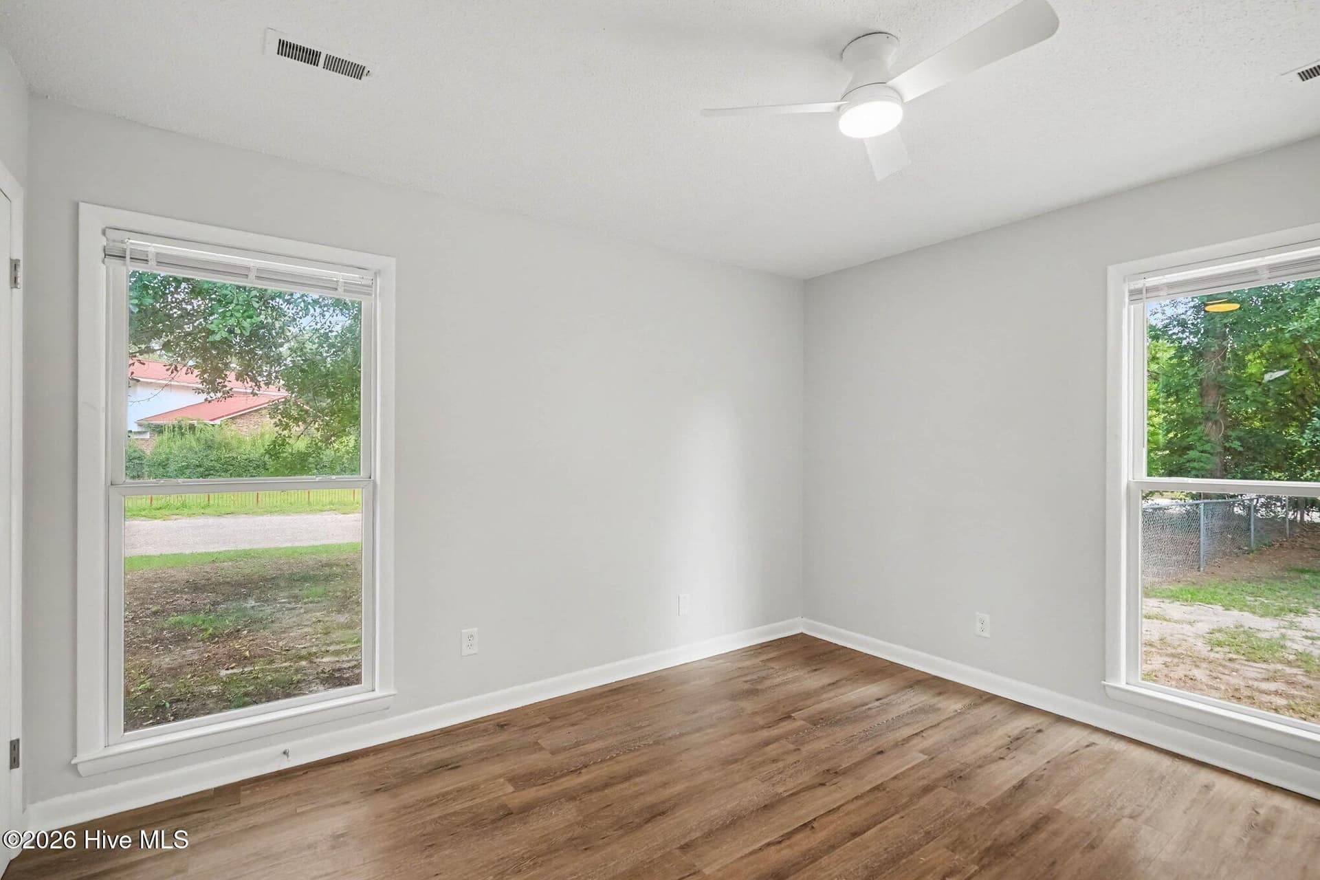 Sun-drenched secondary bedroom featuring dual windows for exceptional natural light, neutral paint, and an updated modern ceiling fan. - 108 Deerfield Drive, Spring Lake, NC 28390