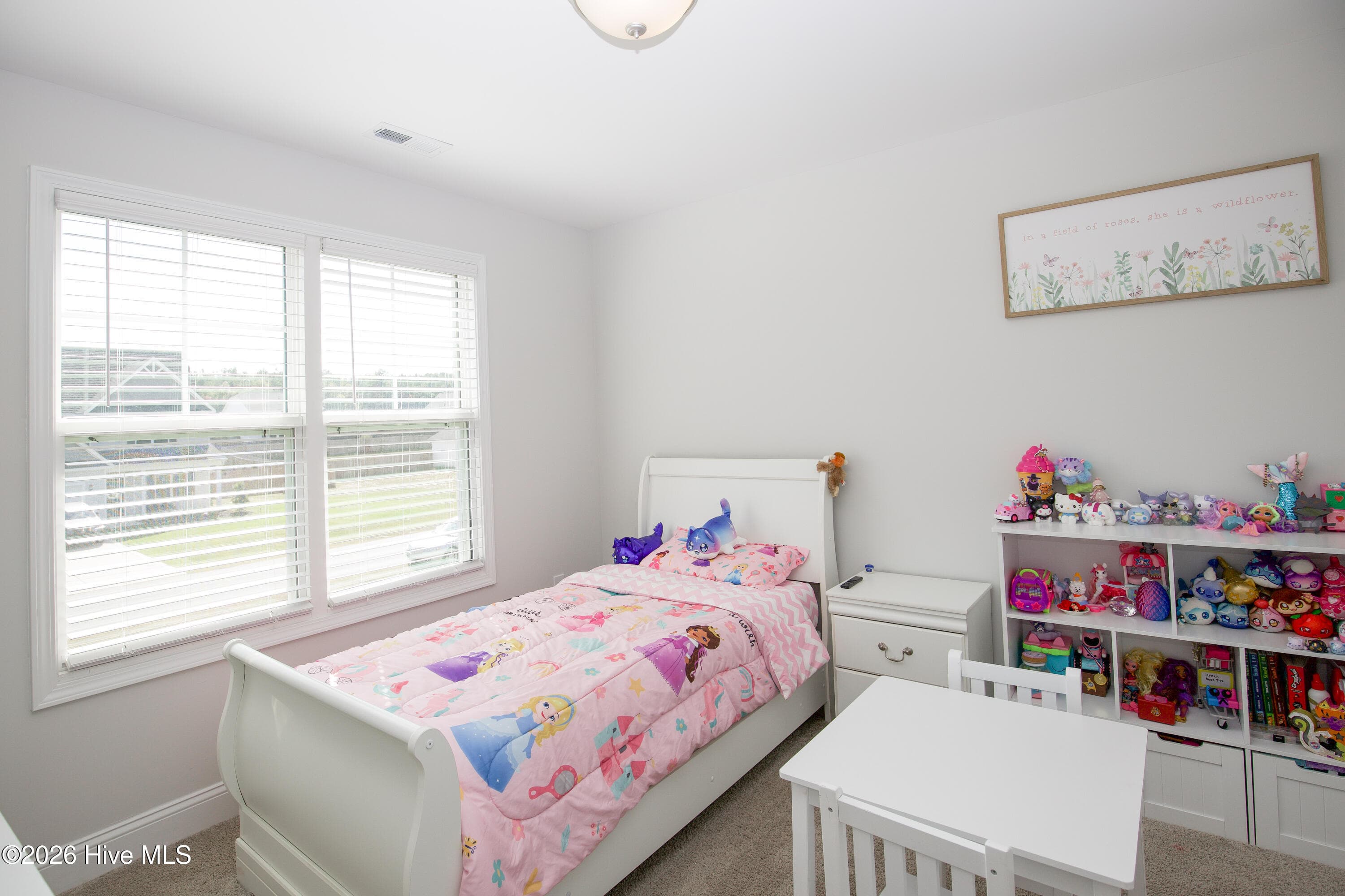 A wide double window fills the third bedroom with natural light and looks out over the front of the property. The room has space for a bed, nightstand, and storage shelving along the walls. Window blinds are already in place. - 221 Vega Lane, Linden, NC 28356