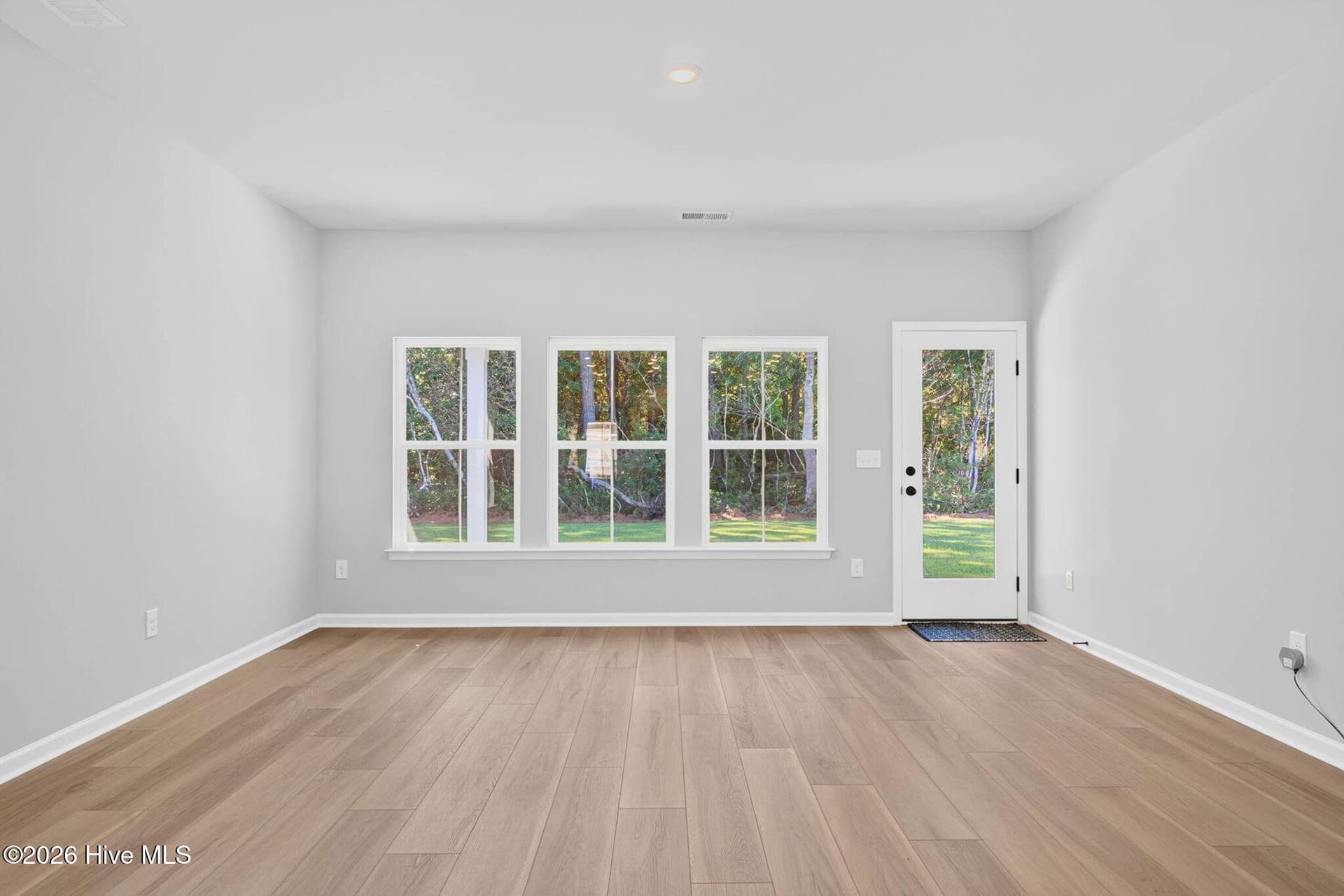 Spacious family room featuring luxury vinyl plank flooring, recessed lighting, and windows overlooking the backyard. - 3447 Sandhill Crane Drive SW, Ocean Isle Beach, NC 28469