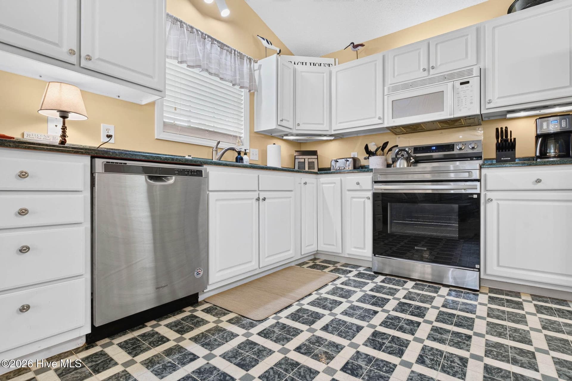 Bright kitchen featuring white cabinetry, stainless steel appliances, and generous counter and cabinet space. - 1650 Frink Street SW, Ocean Isle Beach, NC 28469