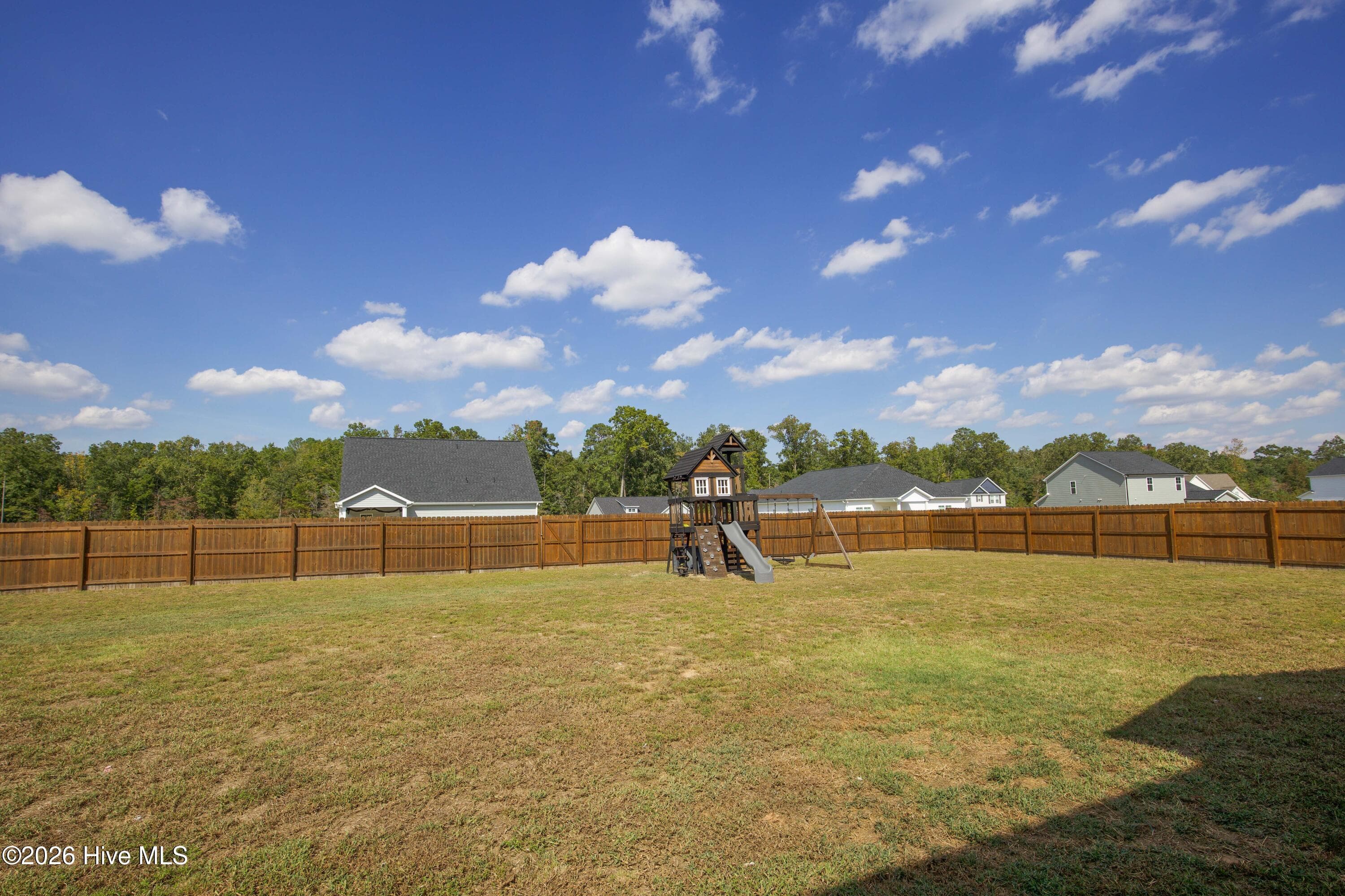 The fenced backyard is one of this home's standout features, with a wood privacy fence enclosing a broad, mostly level lawn. The playground equipment sits at the back of the yard, leaving plenty of open grass in front. Set on approximately 0.46 acre in Linden, this is a newer home in the Fort Bragg area with real outdoor room to work with. - 221 Vega Lane, Linden, NC 28356