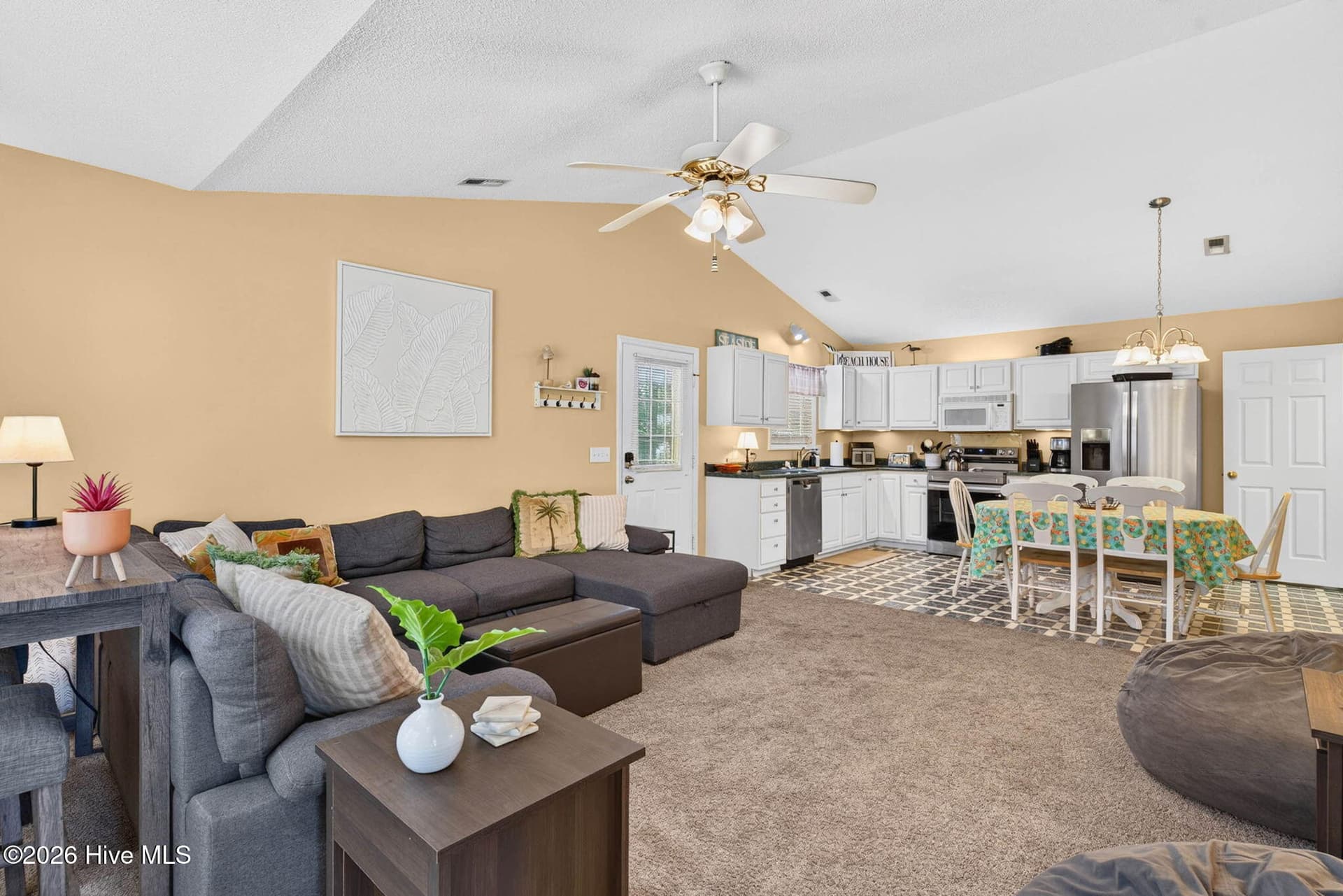 Open living, dining, and kitchen spaces create an easy-flowing layout beneath airy cathedral ceilings. - 1650 Frink Street SW, Ocean Isle Beach, NC 28469