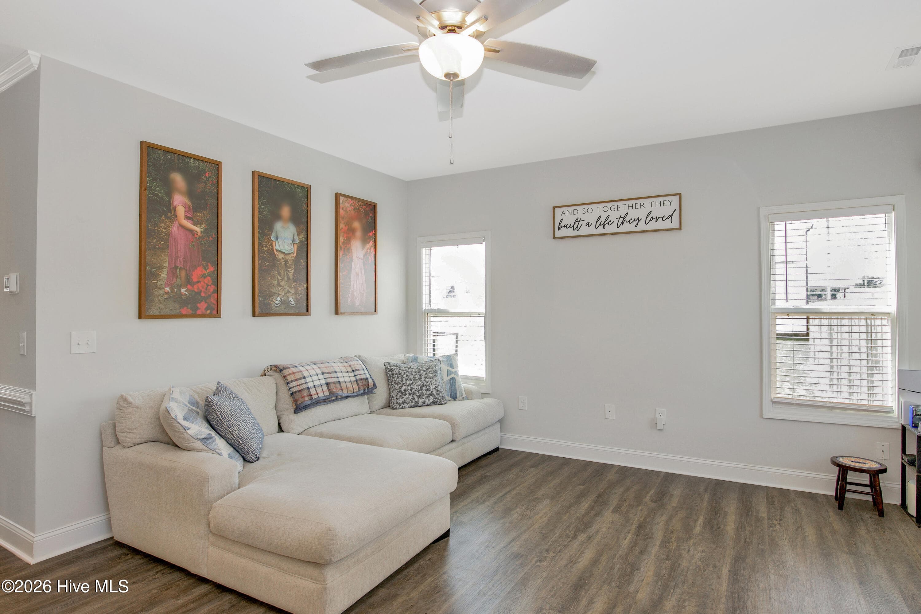 The opposite side of the Great Room offers a long wall for a sofa or sectional, with windows bringing in light from two directions. A ceiling fan with a light kit helps keep the room comfortable. This is the main gathering space on the first floor, set apart from the kitchen work area but still open to it. - 221 Vega Lane, Linden, NC 28356