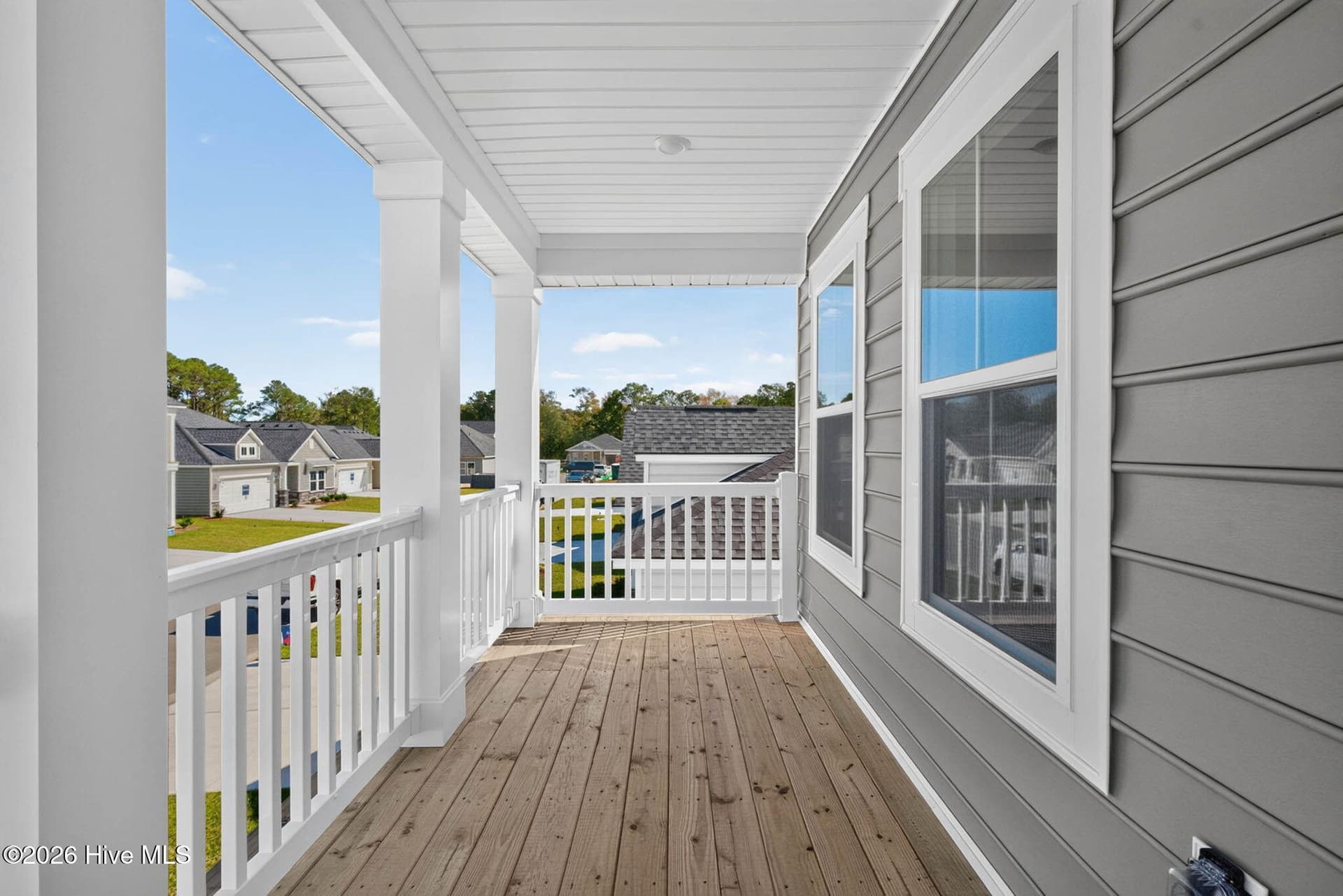 Covered second-floor balcony with outdoor seating space and neighborhood views. - 3447 Sandhill Crane Drive SW, Ocean Isle Beach, NC 28469
