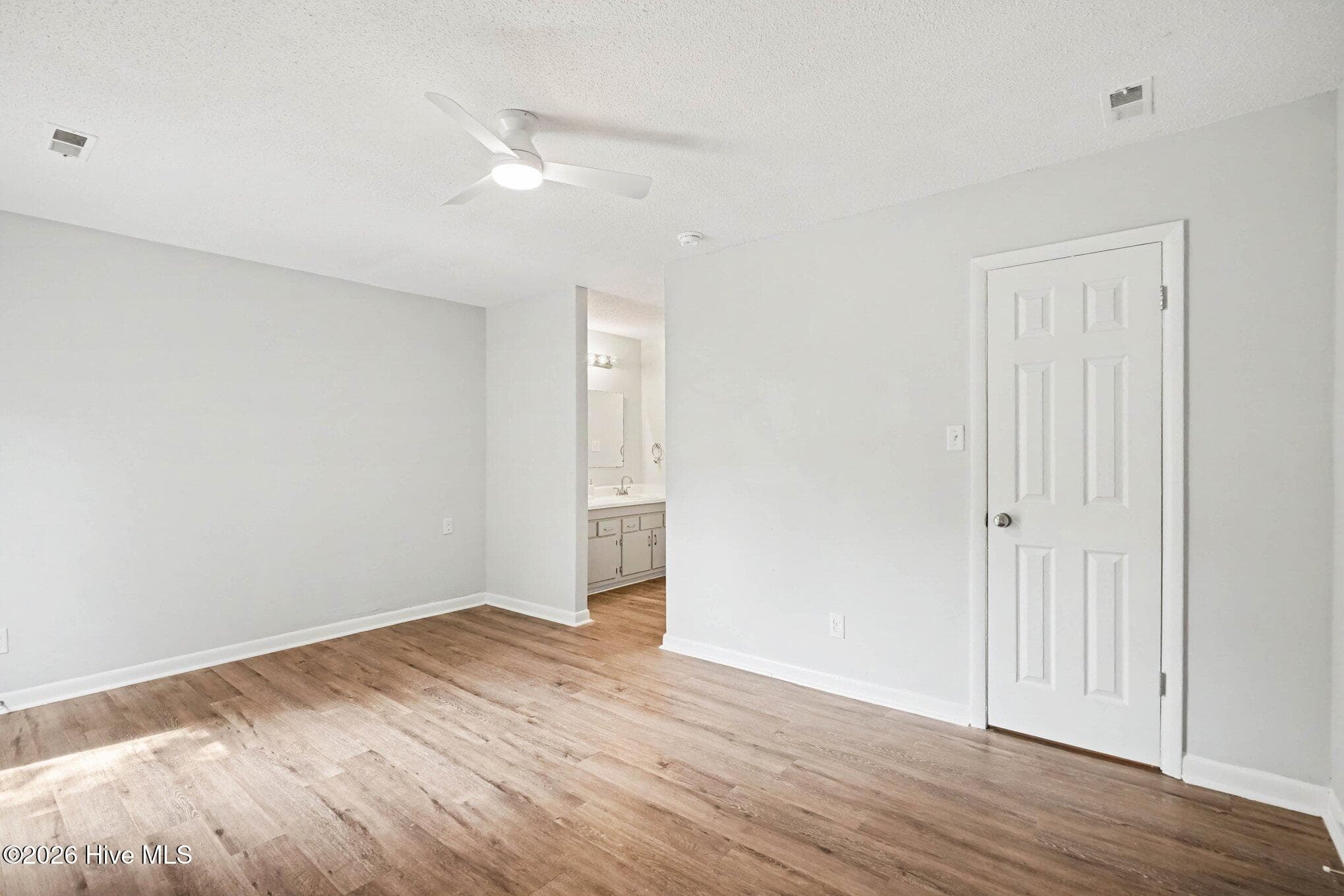 Alternate view of the primary suite highlighting direct ensuite bathroom access, walk-in closet, neutral paint, and an updated ceiling fan for extra comfort. - 108 Deerfield Drive, Spring Lake, NC 28390