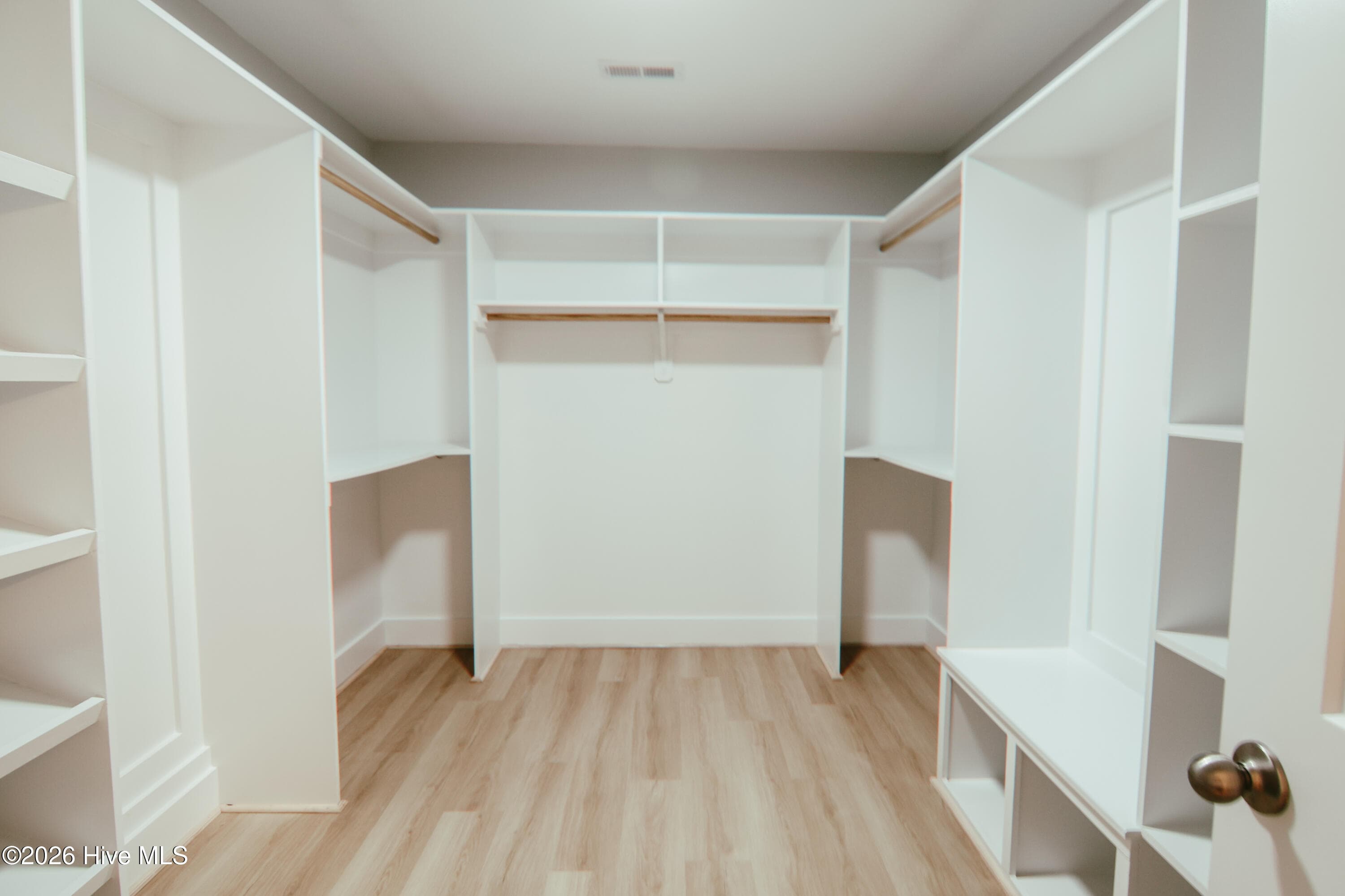 oversized walk-in closet featuring custom shelving, a bench, and shoe racks - 223 Glenwood Trail, Goldsboro, NC 27534