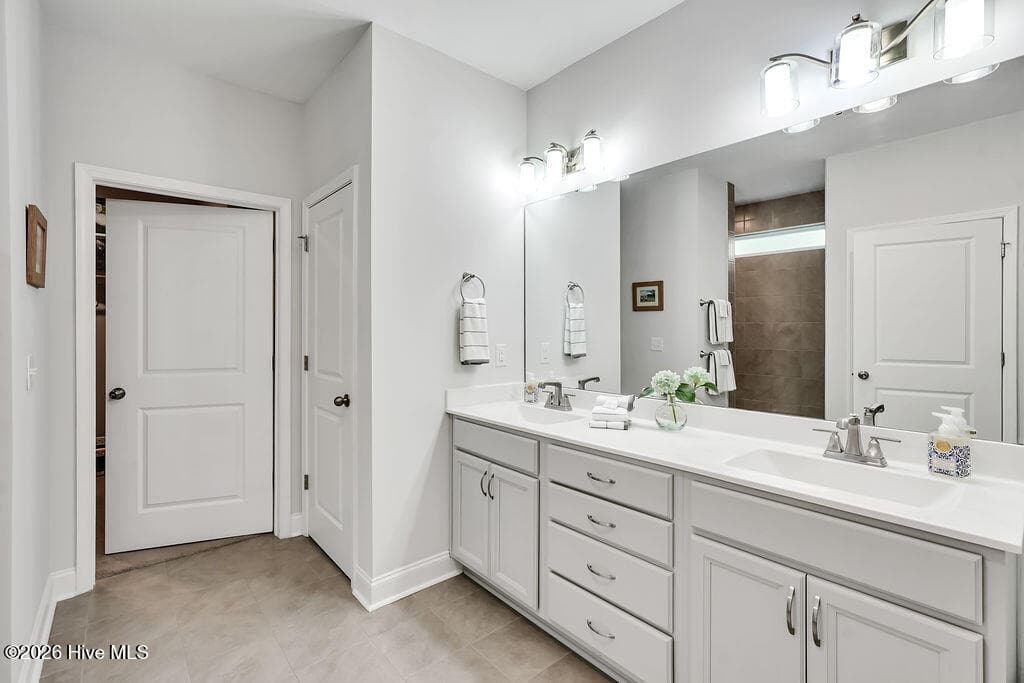 The owner's suite bathroom features spa-like details such as an upgraded L-shaped tiled shower, transom window upgrade, solar tube style sun tunnel, double sink vanity and two spacious walk-in closets. One of these passes through to the laundry room with its built-in folding station. - 142 Rice Marsh Way, Wilmington, NC 28412