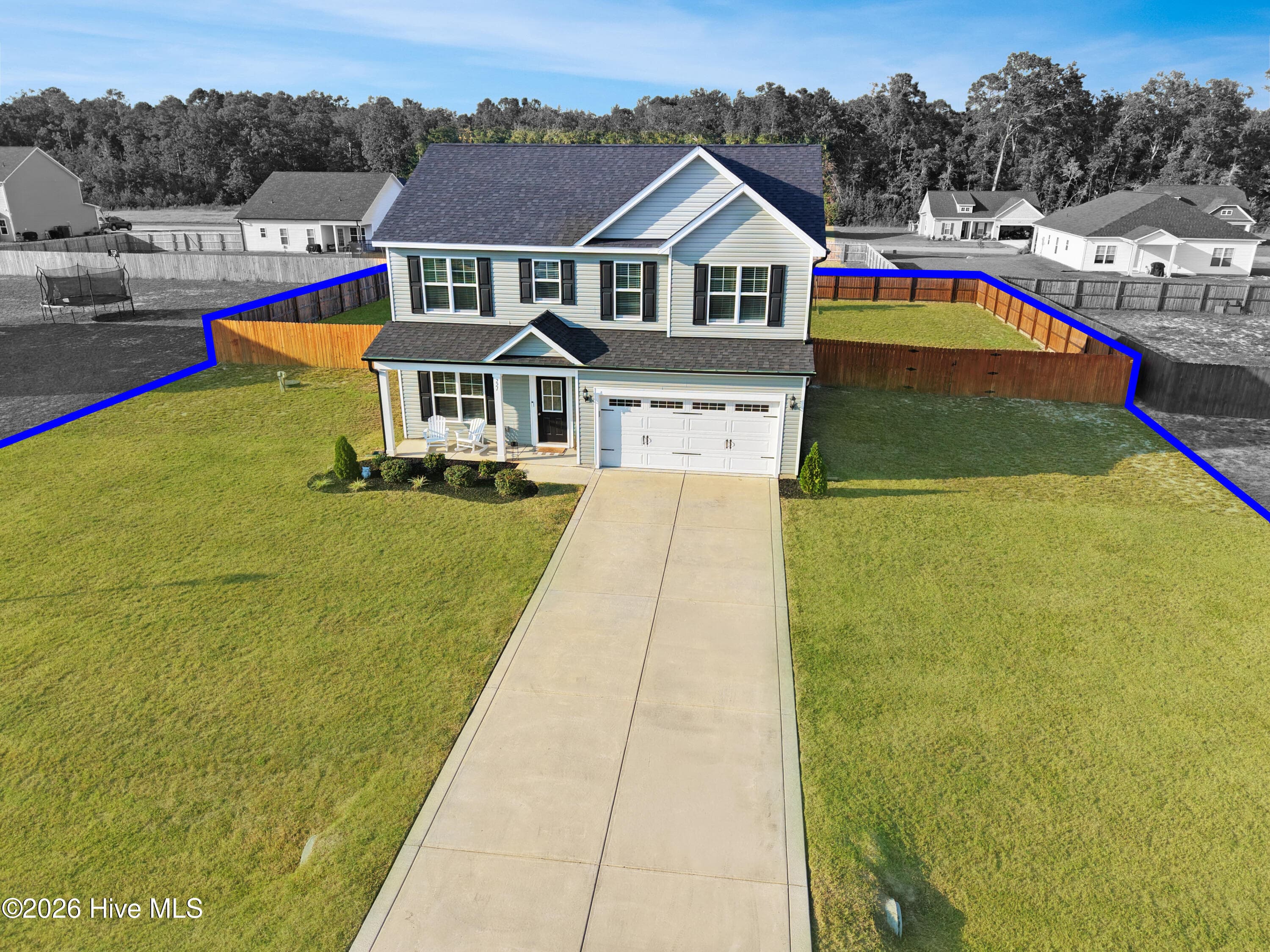Closer aerial view of 221 Vega Lane highlighting the two-story home, attached two-car garage, fenced backyard, covered outdoor area, and usable lot space in Collier Gate. The image has been virtually enhanced, including selective color treatment, to help distinguish the subject property from surrounding properties. Any boundary indicators are approximate and provided solely for marketing reference, not as a survey or representation of legal boundaries. Buyers should independently verify lot lines and property boundaries during due diligence - 221 Vega Lane, Linden, NC 28356