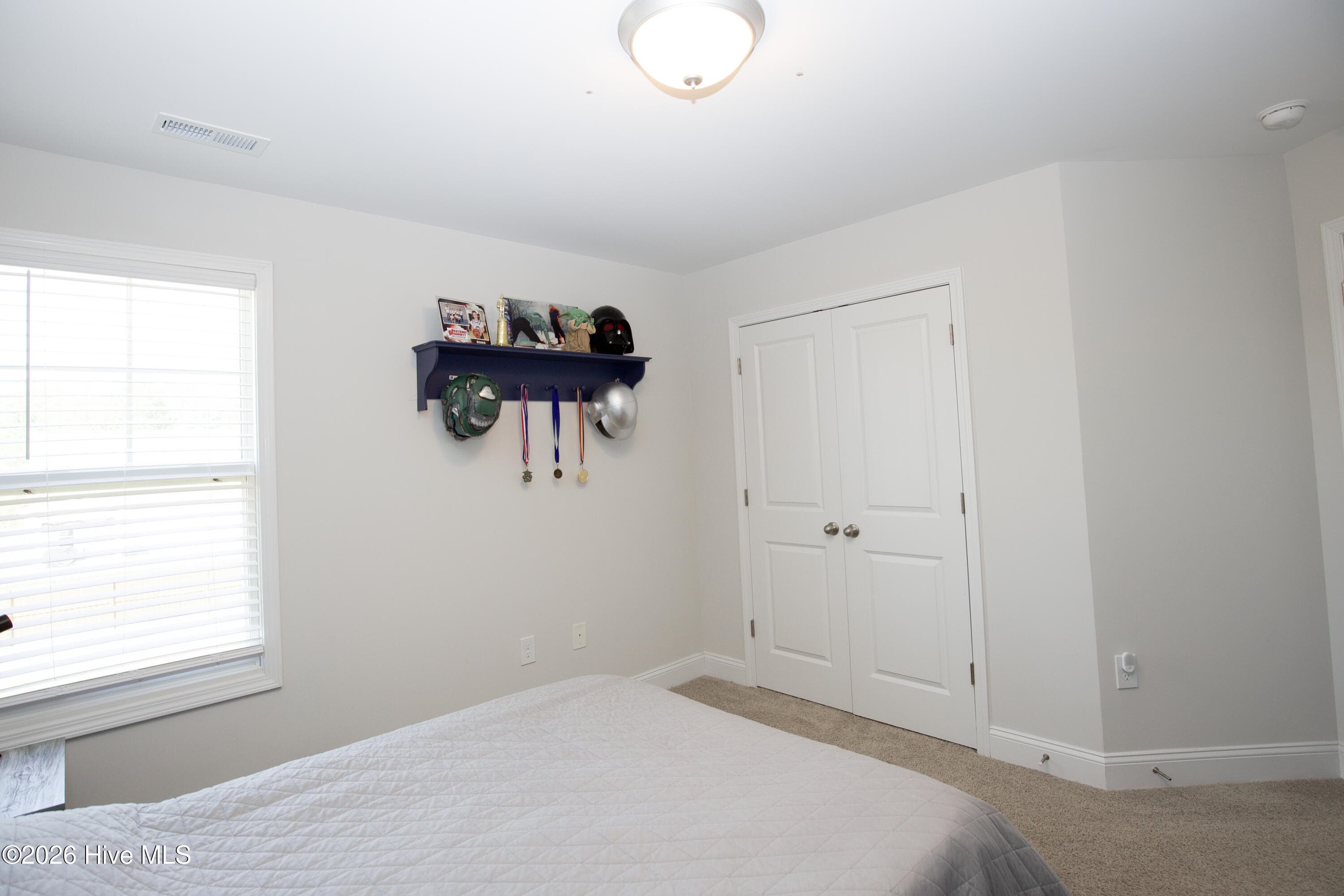 Looking toward the outside wall, the second bedroom has a large window and the double-door closet on the adjoining wall. The neutral walls and carpet make it easy to set the room up as a bedroom, guest room, or office. According to the floor plan, the secondary bedrooms have 8-foot ceilings. - 221 Vega Lane, Linden, NC 28356