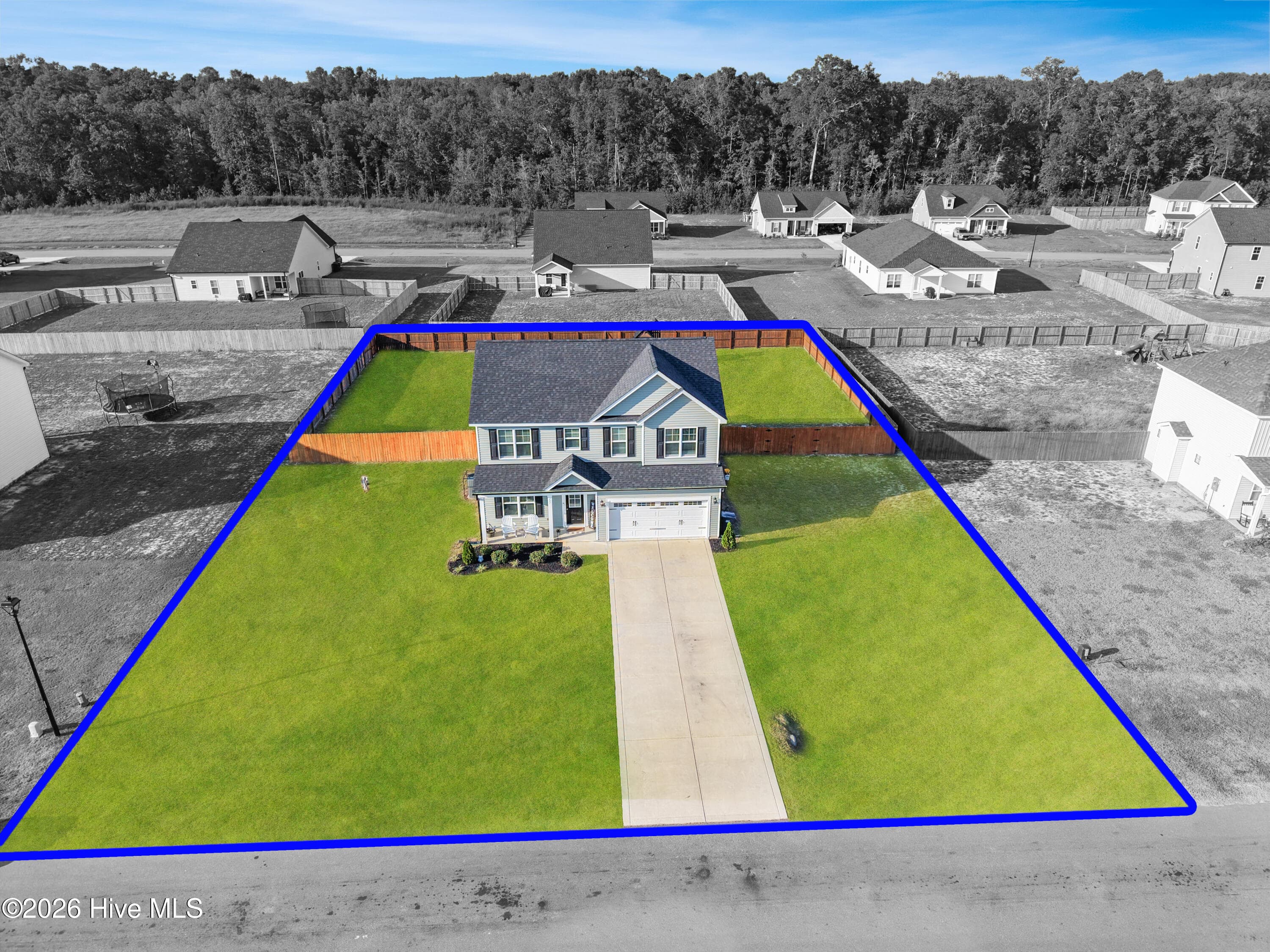 Wide aerial view of 221 Vega Lane in Linden, NC, showing the 2024-built home, approximately 0.46-acre lot, fenced backyard, driveway, and surrounding Collier Gate neighborhood. Image has been virtually enhanced, including selective color treatment, to help illustrate the subject property in relation to neighboring surroundings. Any boundary indicators shown are approximate, for marketing reference only, and do not represent surveyed property lines. Buyers are encouraged to verify property boundaries through a current survey and other appropriate due diligence. - 221 Vega Lane, Linden, NC 28356