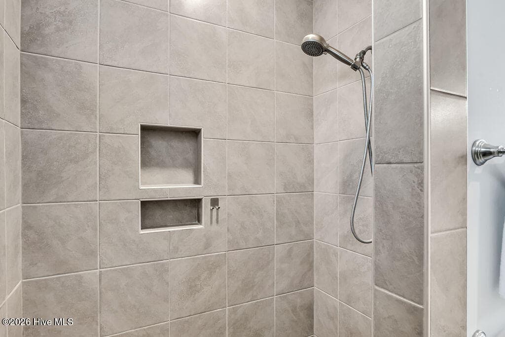 The owner's suite bathroom features spa-like details such as an upgraded L-shaped tiled shower, transom window upgrade, solar tube style sun tunnel, double sink vanity and two spacious walk-in closets. One of these passes through to the laundry room with its built-in folding station. - 142 Rice Marsh Way, Wilmington, NC 28412