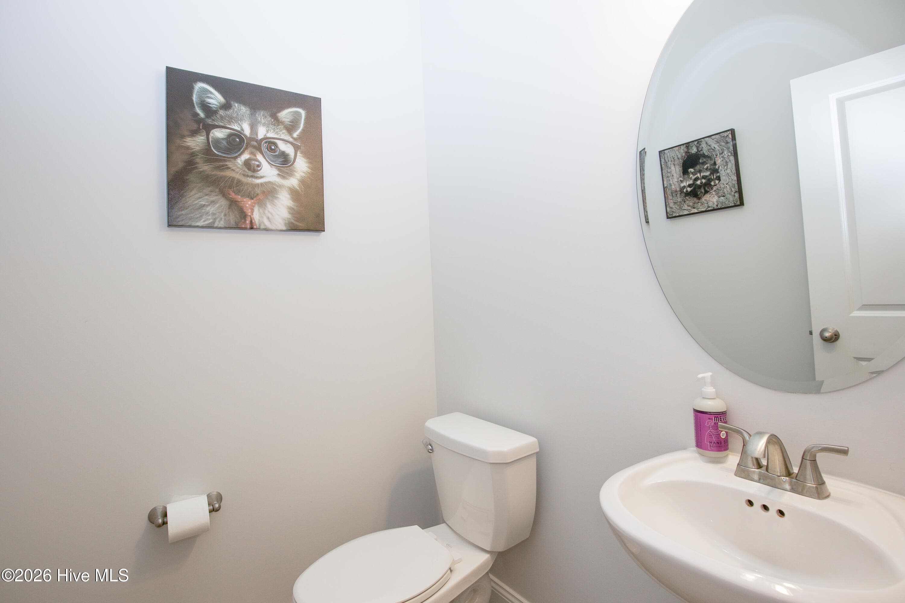 The main-level half bath includes a pedestal sink, a wall mirror, and a toilet, finished with the same flooring used throughout the first floor. Its placement off the front hall means guests do not need to go upstairs. Together with the two full baths on the second floor, it gives this home its two-and-a-half-bath layout. - 221 Vega Lane, Linden, NC 28356