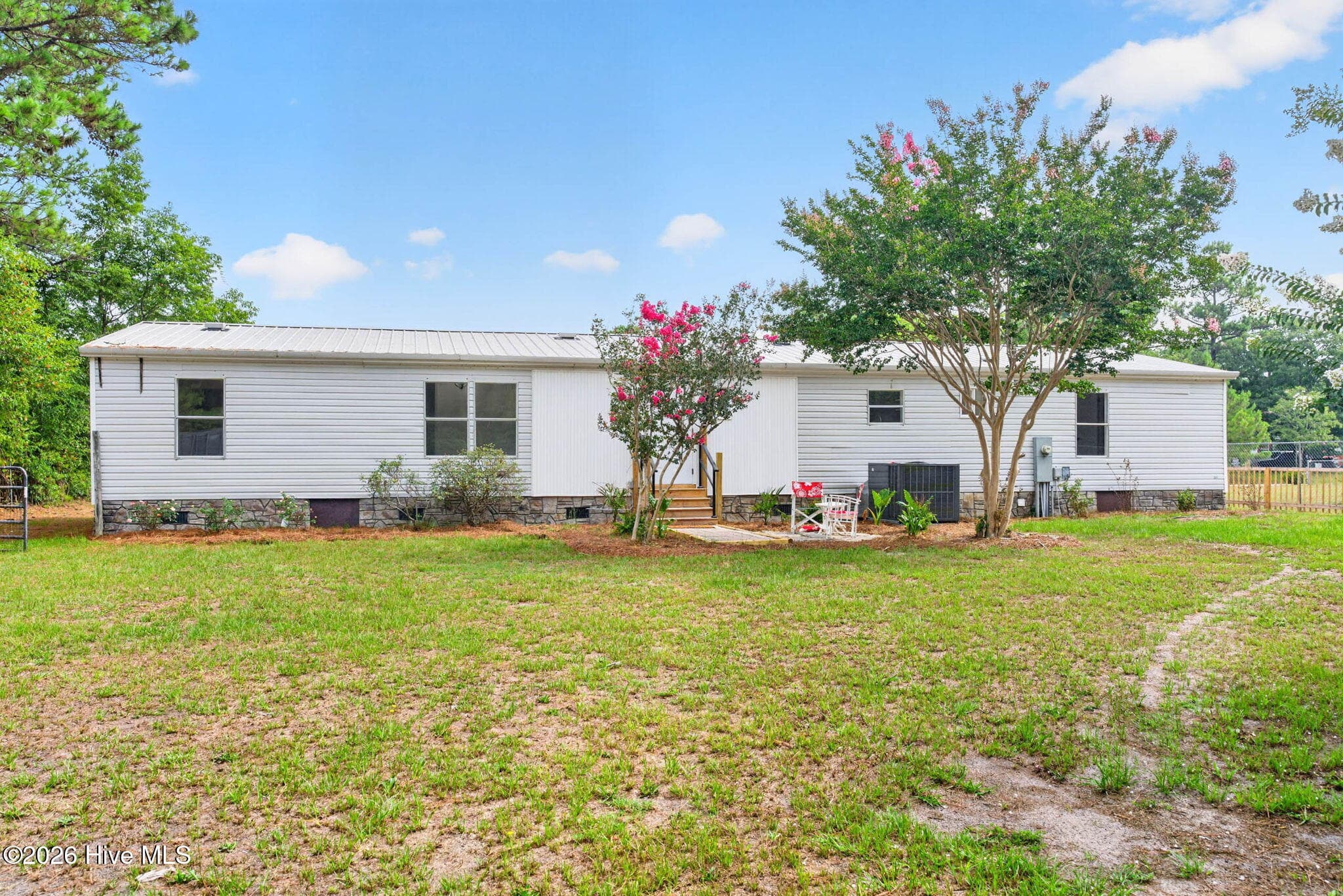 A wide back elevation showcases this beautifully renovated home set on a generous 0.57-acre lot with mature trees and outstanding curb appeal. - 1199 Zack Street SE, Bolivia, NC 28422