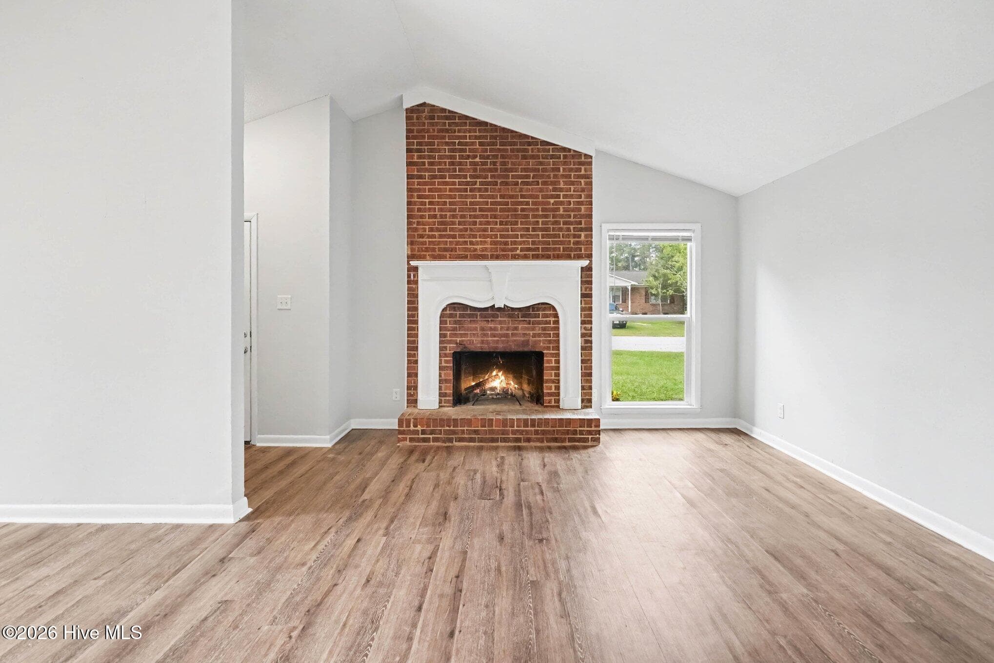 Spacious living room anchored by a stunning floor-to-ceiling, wood burning brick fireplace with raised hearth, vaulted ceiling, neutral palette, and sized to accommodate a variety of seating arrangements. - 108 Deerfield Drive, Spring Lake, NC 28390