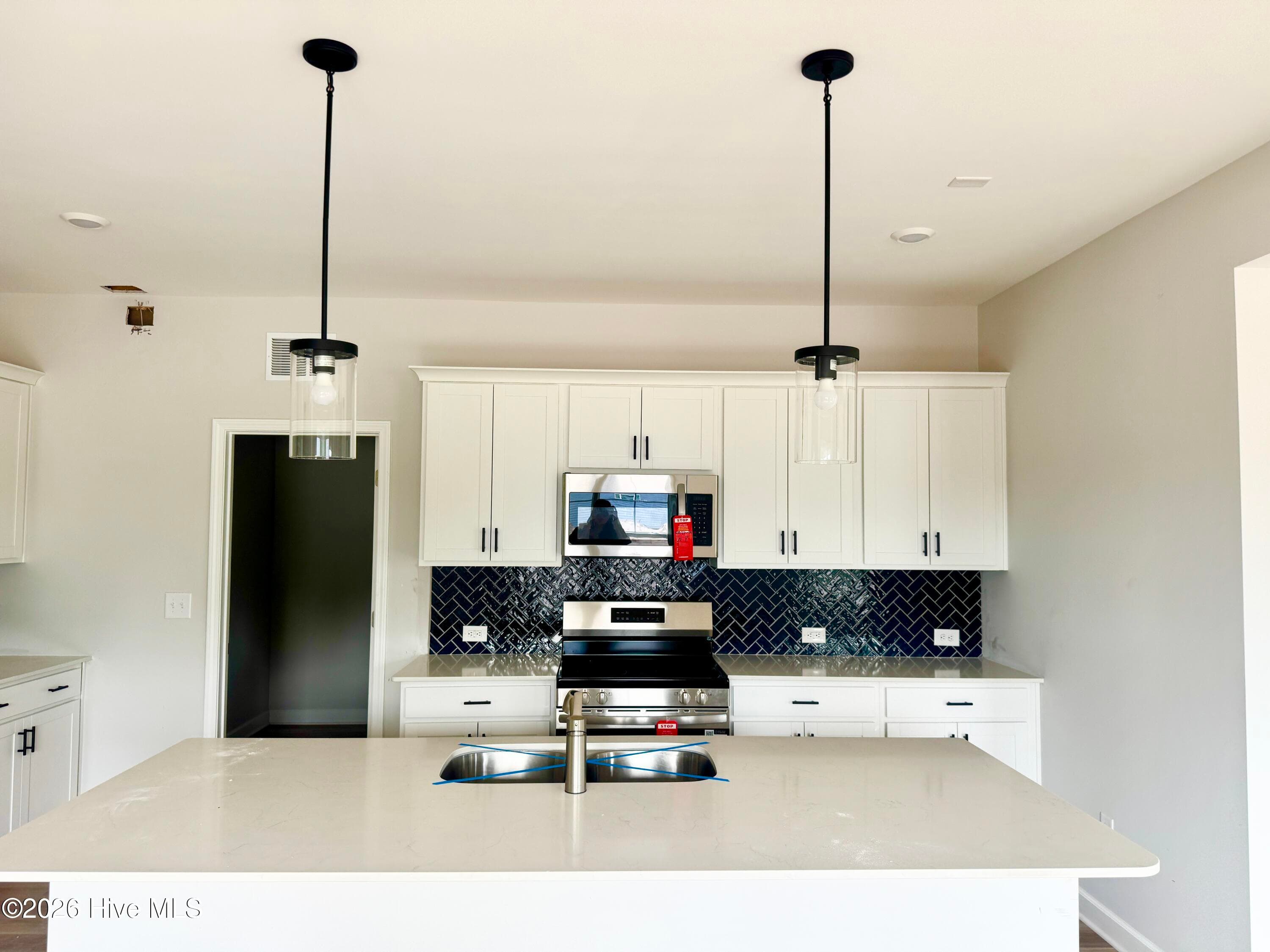 Stunning Kitchen includes Quartz Countertops, Stainless Appliances, Tile Backsplash, Beautiful Lighting fixtures and an abundance of Cabinets. - 4208 Workman Loop 94, Leland, NC 28451