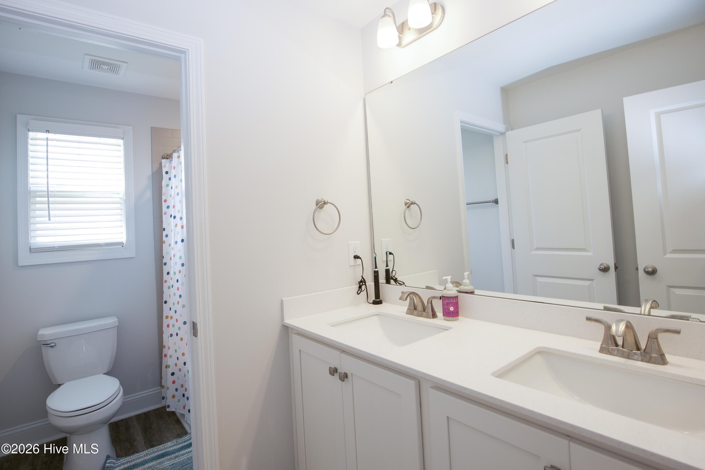 The second full bath upstairs includes a double vanity with two sinks and a large mirror. A door separates the vanity area from the toilet and tub/shower, so one person can use the sinks while another uses the bath. This layout is helpful on busy mornings with several people getting ready at once. - 221 Vega Lane, Linden, NC 28356