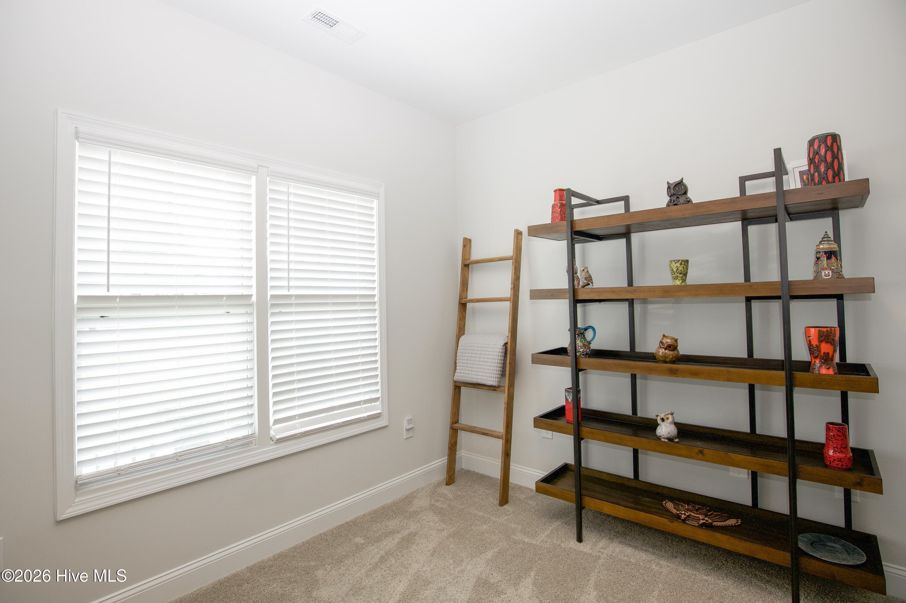 This view of the flex room shows how it can work for more than one use, with room for shelving, a reading chair, or hobby supplies. According to the professional floor plan, the room measures approximately 10'6" by 10'10" with a 9-foot ceiling. It could serve as a home office, sitting room, or hobby space, depending on what you need. - 221 Vega Lane, Linden, NC 28356