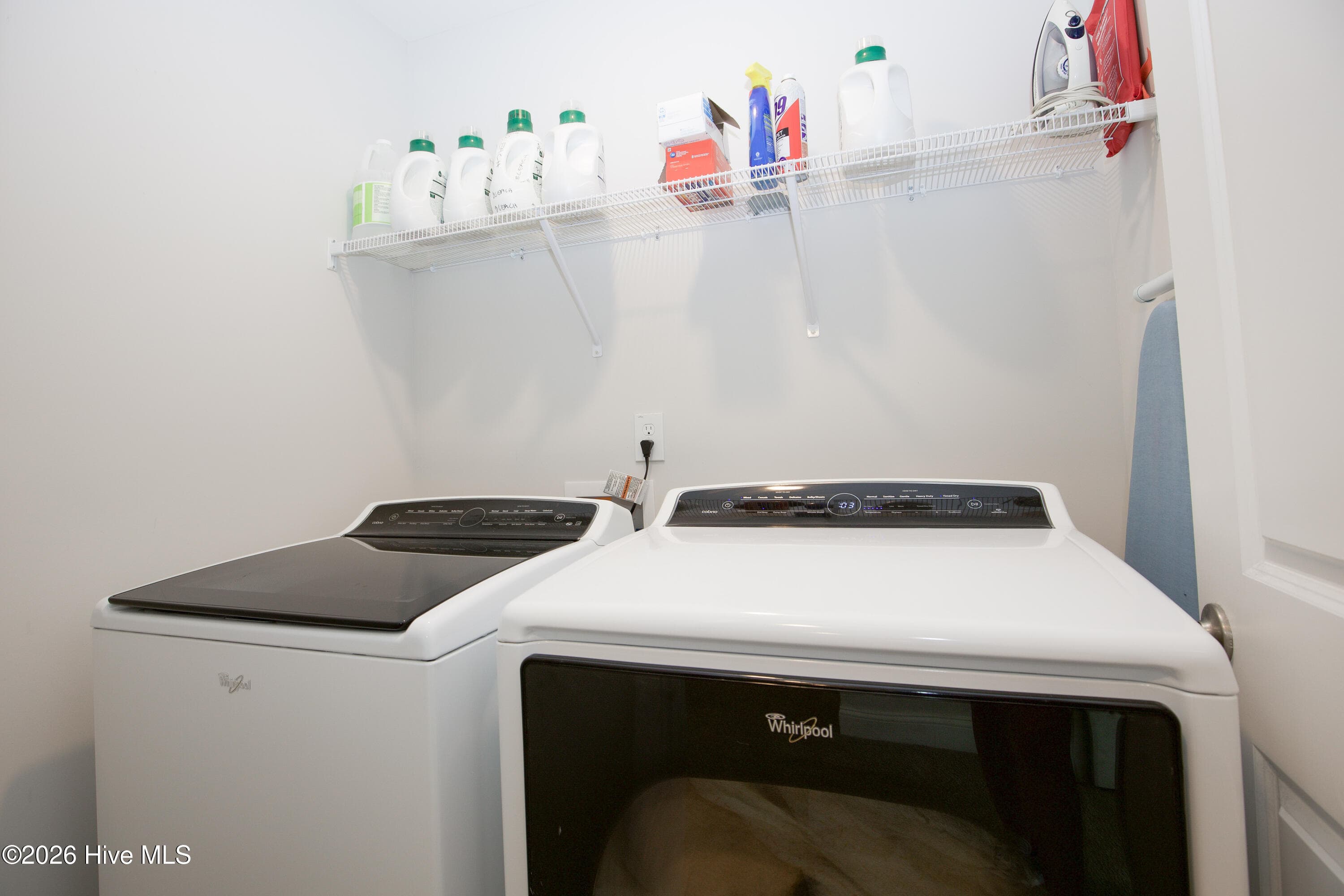 The upstairs laundry room has a wire shelf above the machines for detergent and supplies. The washer and dryer shown here convey with the home. The room's location near all four bedrooms keeps laundry close to where it is used. - 221 Vega Lane, Linden, NC 28356