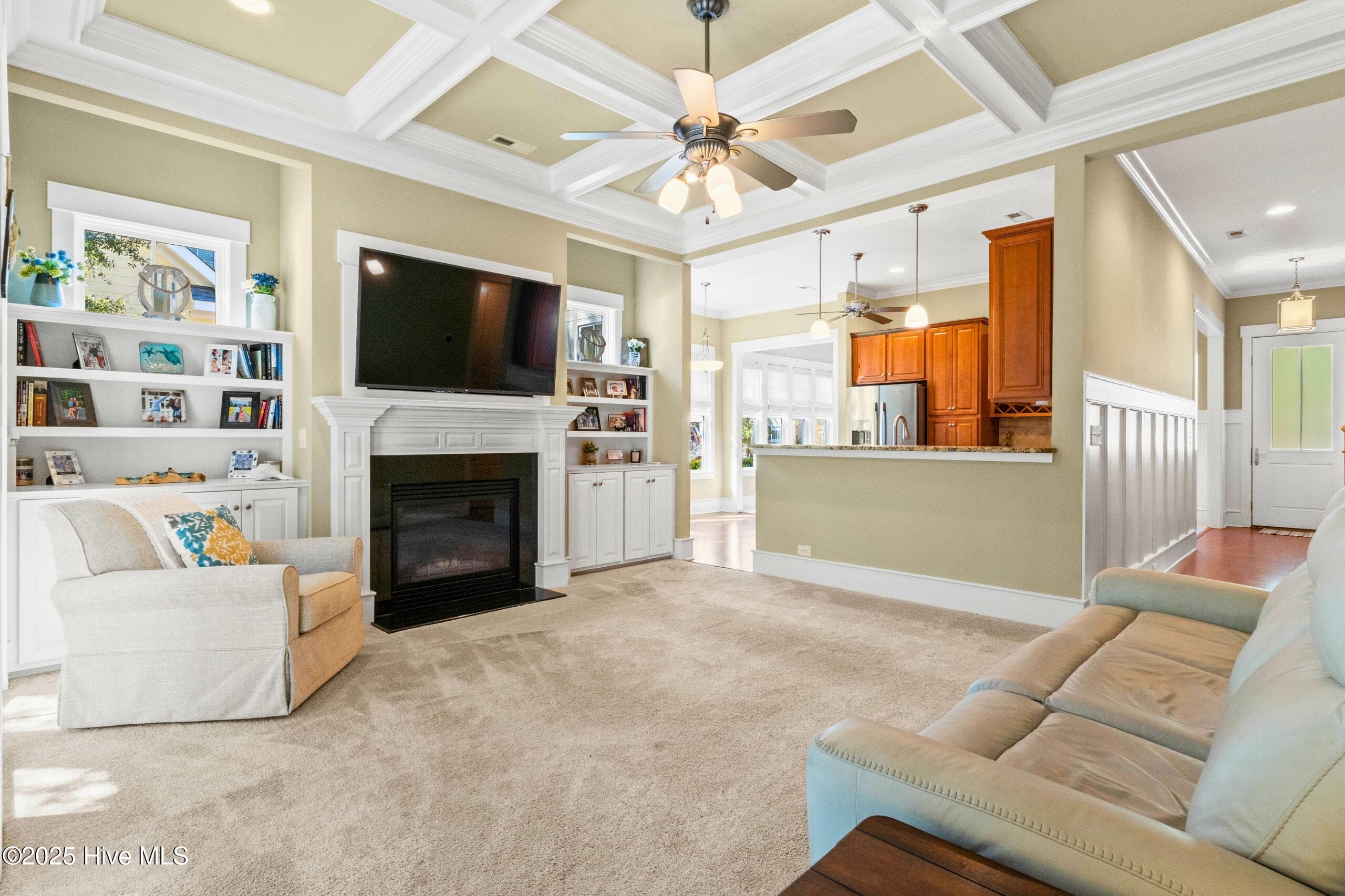Spacious open-concept living area highlighting a custom coffered ceiling, gas log fireplace, built-in cabinetry, and abundant natural light. - 9100 Fountain Street SW, Calabash, NC 28467
