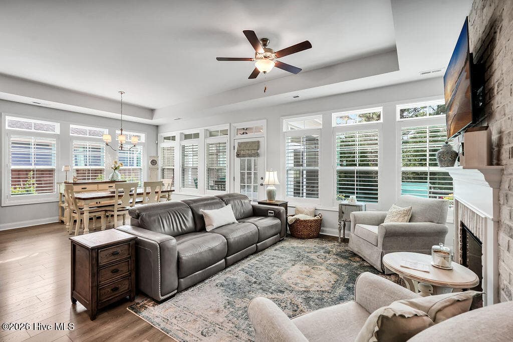 The living and dining areas are beautifully drenched in sunlight thanks to a bank of large, energy-efficient Low-E windows. Outfitted with custom plantation blinds, these windows allow for an easy transition between indoor and outdoor spaces and add an air of southern coastal charm to the neutral seaside color palette. A tray ceiling and an electric fireplace with custom brick surround complete this bright and open space. - 142 Rice Marsh Way, Wilmington, NC 28412
