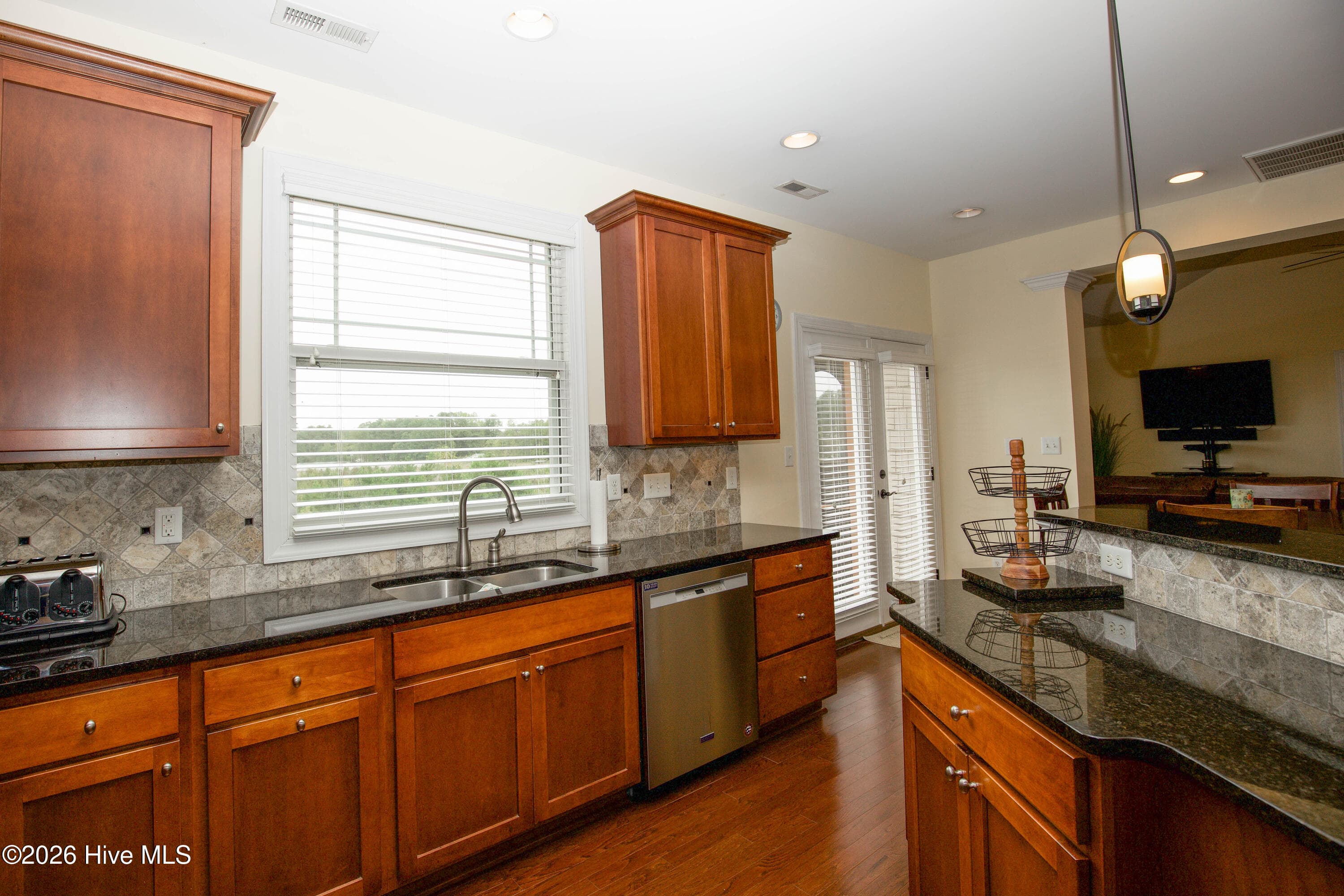 Kitchen sink beneath a window, with the dishwasher and island, open to the breakfast area. - 899 Seagull Drive, Vass, NC 28394, Vass