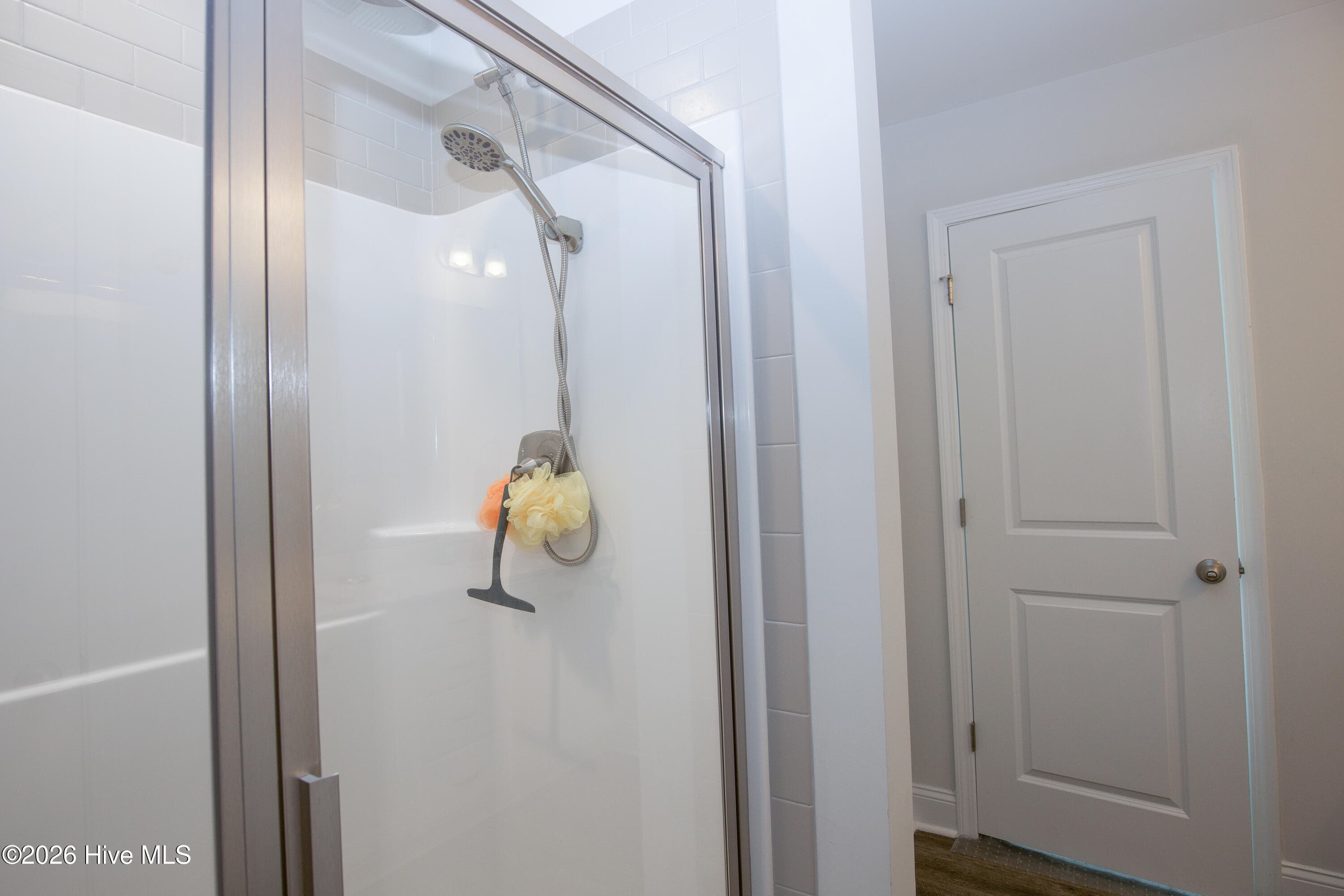Inside the shower, you will find a handheld showerhead on an adjustable slide bar and a framed glass door. The light surround and tile border keep the space bright and easy to clean. The door beside the shower leads to the walk-in closet. - 221 Vega Lane, Linden, NC 28356