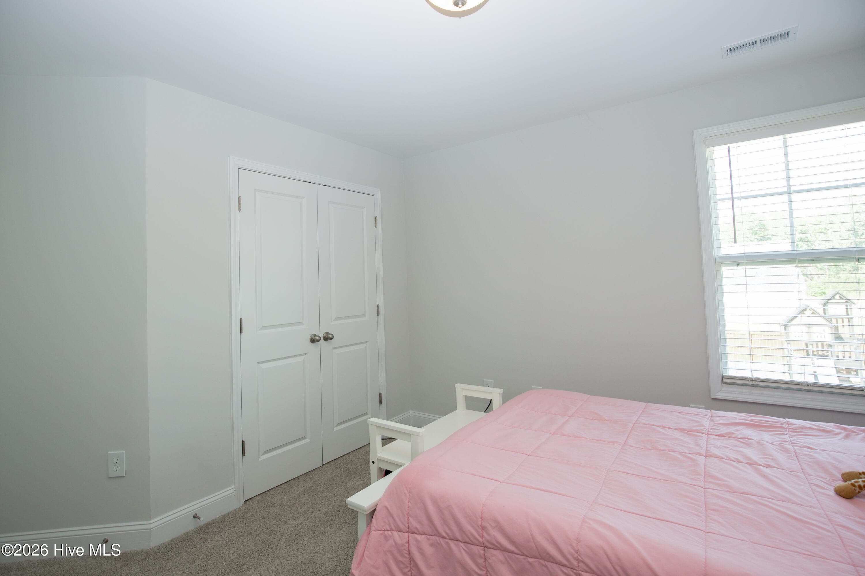 From the fourth bedroom, the window looks out over the backyard, where the playground equipment and fence line are visible. The double-door closet is on the adjacent wall. This rear-facing room overlooks the yard rather than the street. - 221 Vega Lane, Linden, NC 28356
