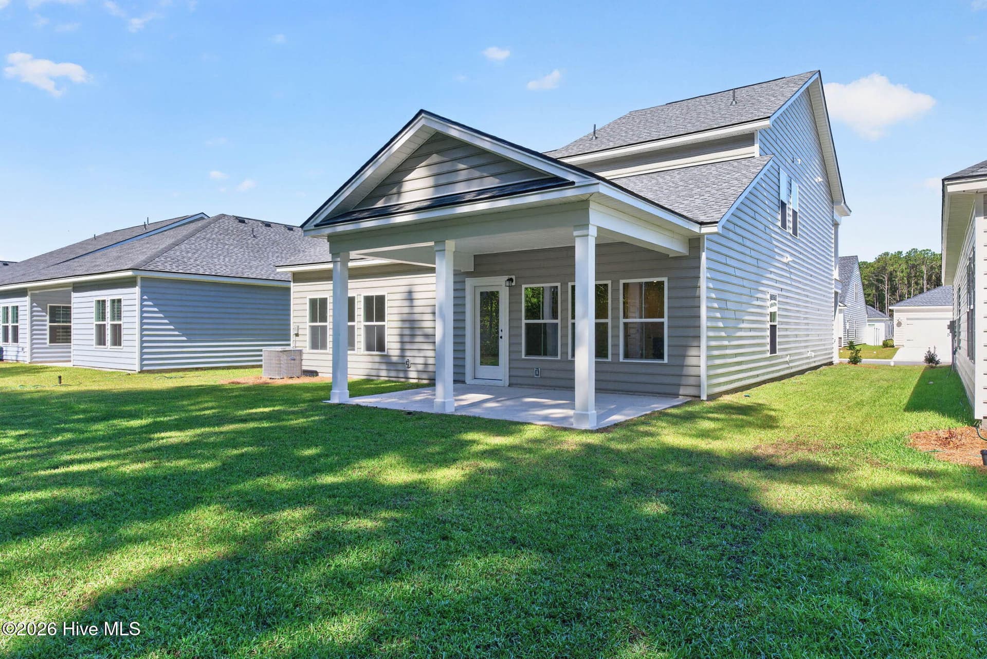 Rear exterior showcasing the covered patio, backyard, and attractive coastal architecture. - 3447 Sandhill Crane Drive SW, Ocean Isle Beach, NC 28469