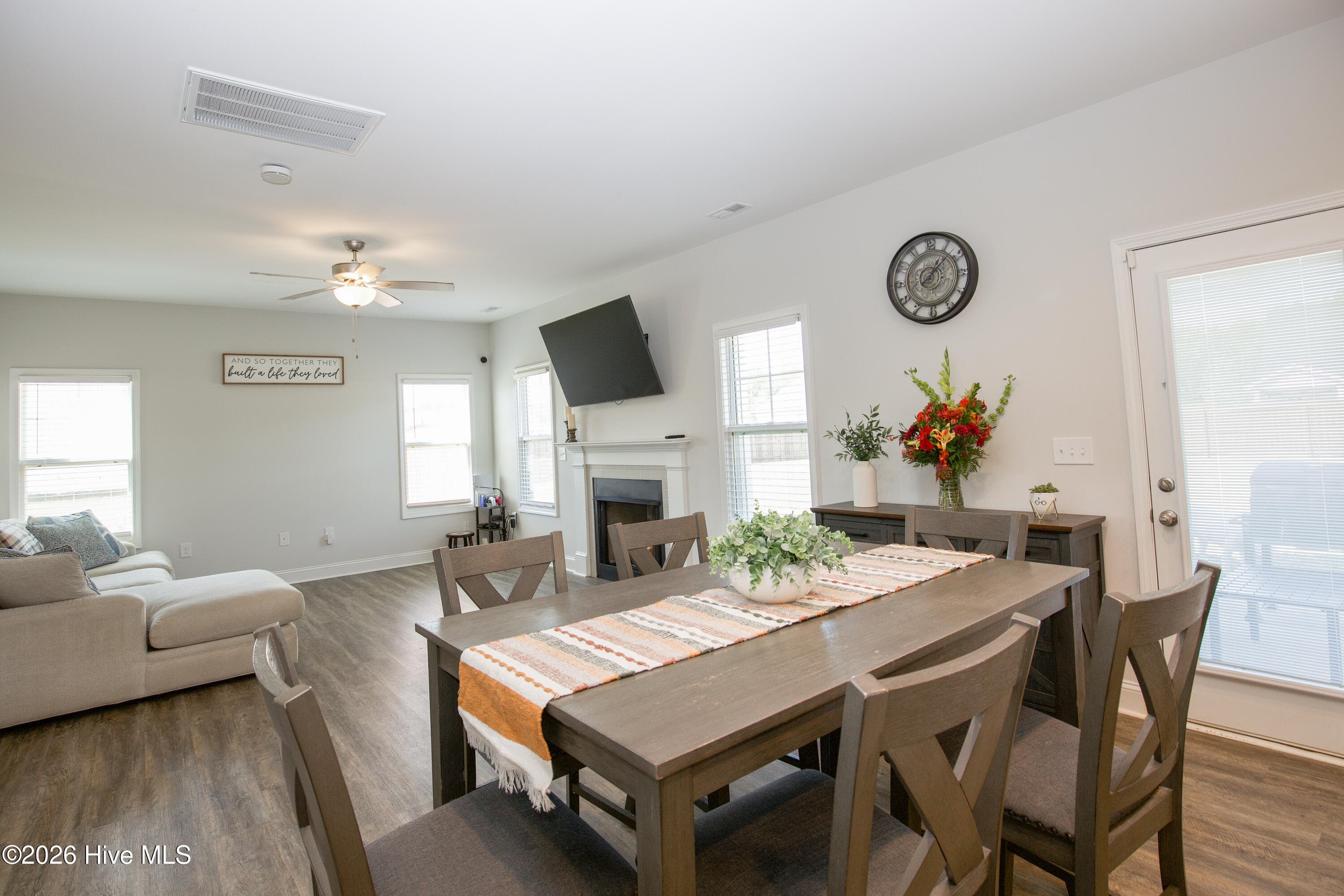 Here the dining area and Great Room come together, with the fireplace and windows across the room and the rear door to the patio on the right. The arrangement makes it easy to move between eating, relaxing, and stepping outside. A ceiling fan in the Great Room and recessed lighting throughout keep the space comfortable and well lit. - 221 Vega Lane, Linden, NC 28356