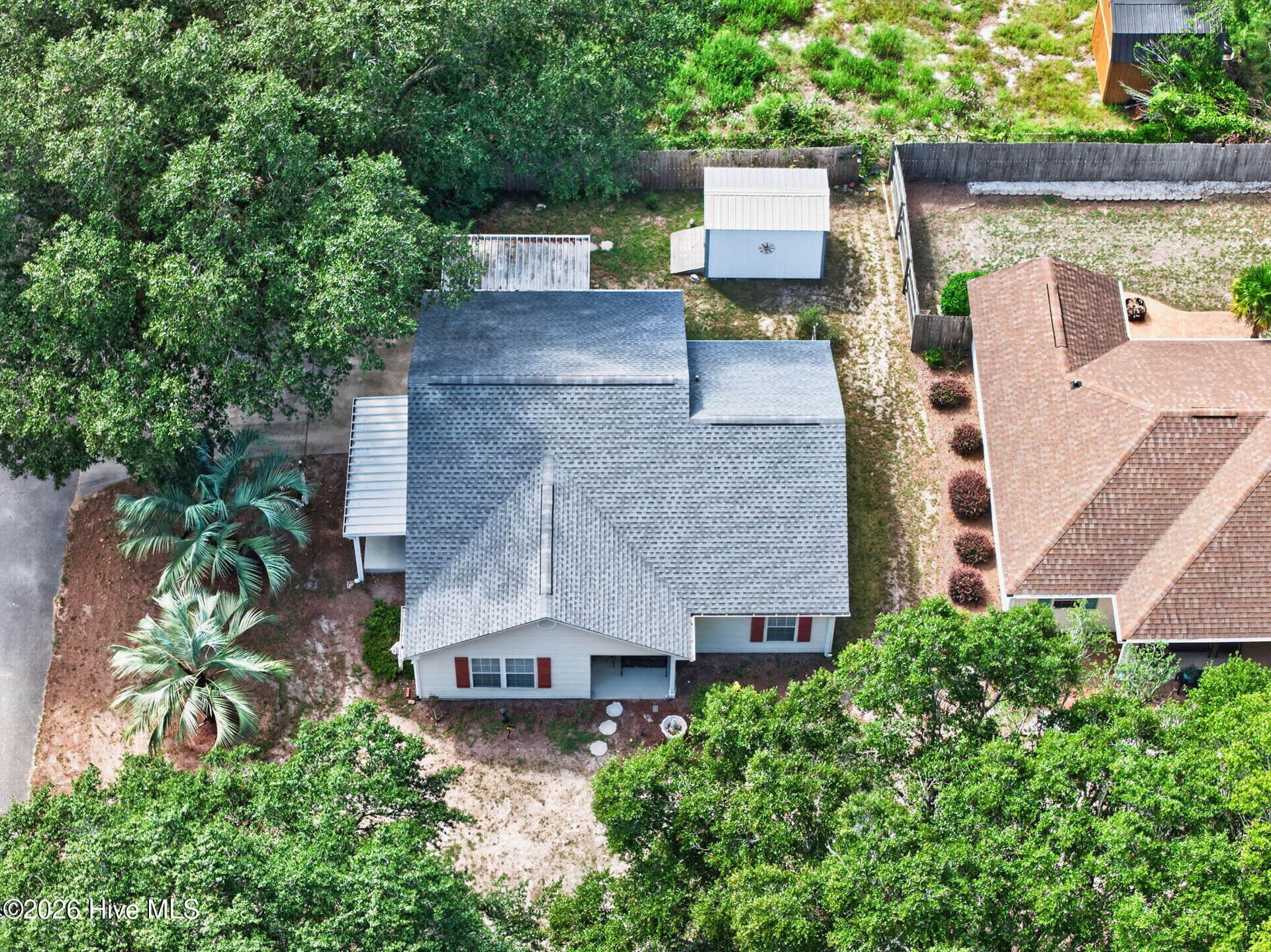 Aerial perspective highlights the home's established setting surrounded by mature coastal greenery. - 1650 Frink Street SW, Ocean Isle Beach, NC 28469