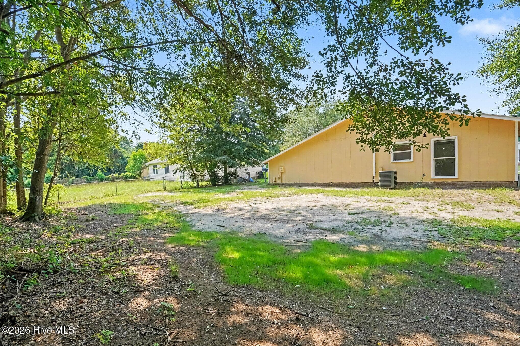 Expansive backyard space framed by mature shade trees, offering a private setting with plenty of potential for outdoor recreation, gardening, or entertaining. - 108 Deerfield Drive, Spring Lake, NC 28390