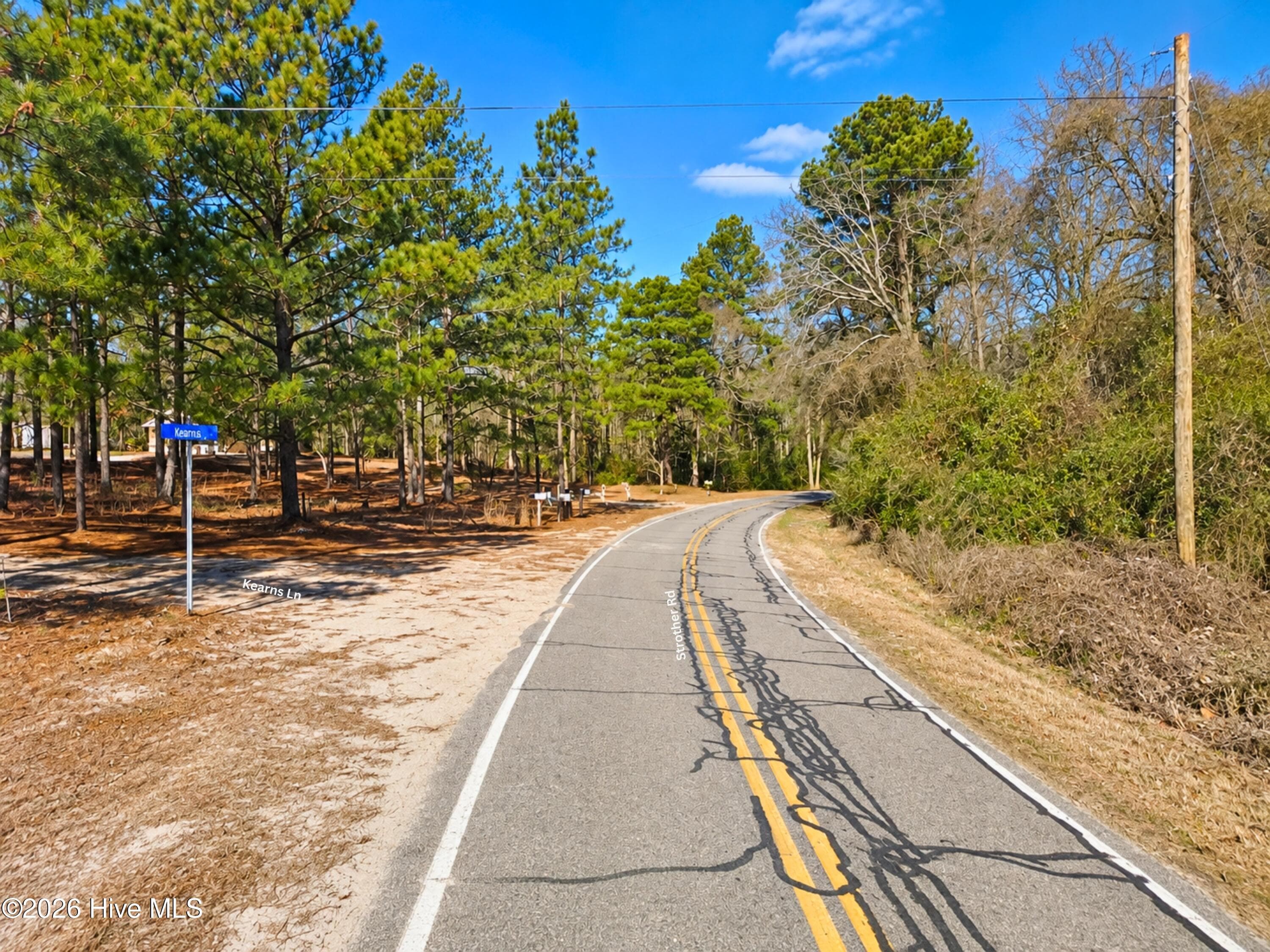 Ground view of paved, state-maintained Strother Rd where Kearns Ln meets the land. Easy year-round access to wooded Hoke County, NC acreage, with power lines along the road. - 00-00 Strother Road, Aberdeen, NC 28315