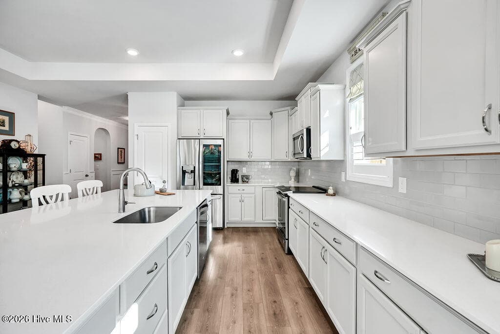 Chef-style kitchen island is the heart of this home and a natural gathering place. The kitchen also features upgraded premium staggered, color glazed cabinetry with dovetails, a single basin stainless sink, fully tiled backsplash throughout, upgraded stainless refrigerator and oven/range, upgraded granite countertops, brushed nickel lighting package, and custom plantation blinds. - 142 Rice Marsh Way, Wilmington, NC 28412