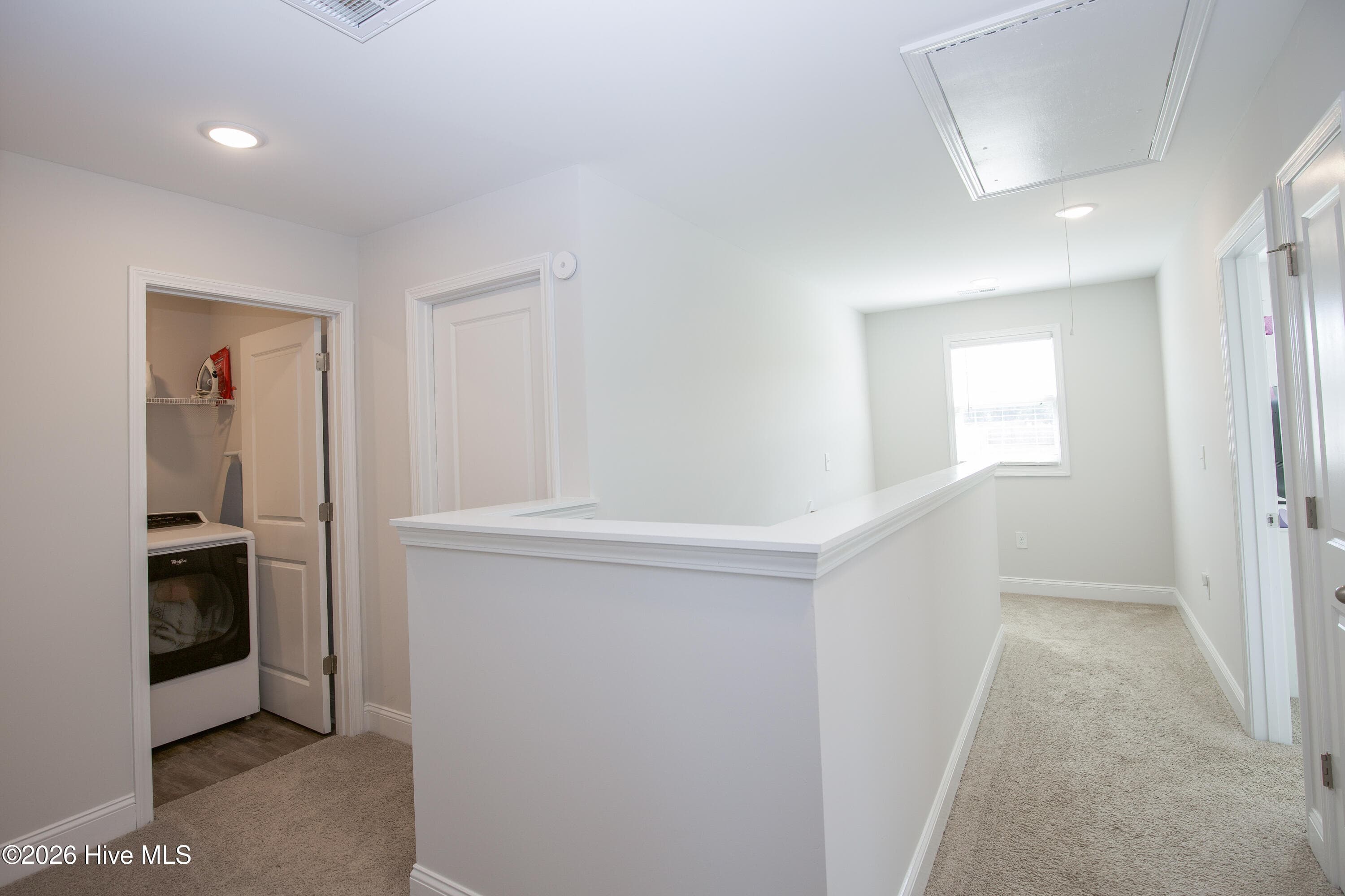 The laundry room opens off the upstairs hall, steps from the bedrooms. Having laundry on the same floor as the bedrooms means no carrying baskets up and down the stairs. The hall continues past the stair opening to a window at the end. - 221 Vega Lane, Linden, NC 28356