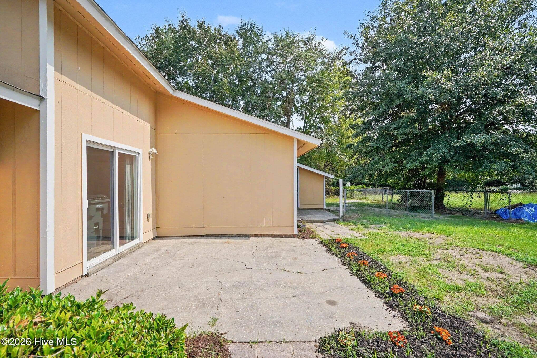 Spacious concrete patio accessed directly from the dining room, ready for grilling, comfy seating or dining arrangements and surrounded by landscaped beds and mature trees. - 108 Deerfield Drive, Spring Lake, NC 28390