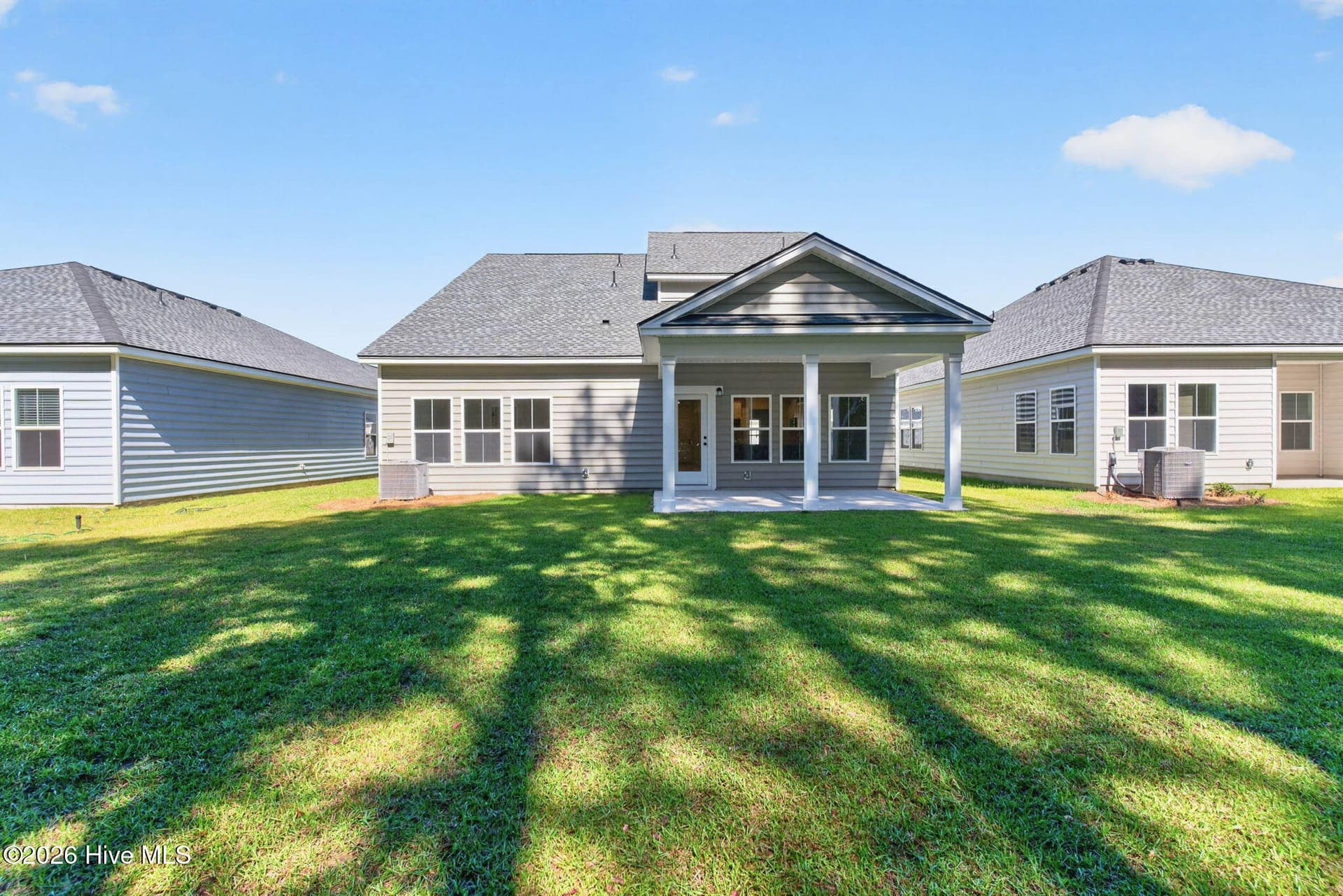 Wide backyard view highlighting the home's two-story design and rear outdoor living space. - 3447 Sandhill Crane Drive SW, Ocean Isle Beach, NC 28469