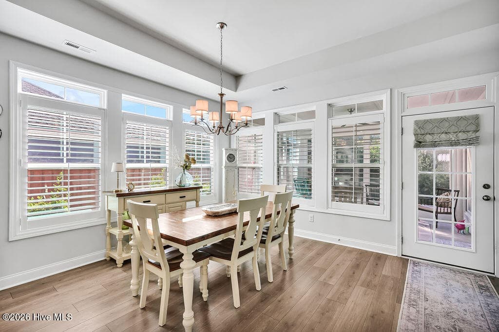 The dining area is absolutely drenched in sunlight thanks to a bank of large, energy-efficient Low-E windows. Outfitted with custom plantation blinds, these windows allow for an easy transition between indoor and outdoor spaces and add an air of southern coastal charm to the neutral Scandi-meets-seaside color palette. - 142 Rice Marsh Way, Wilmington, NC 28412