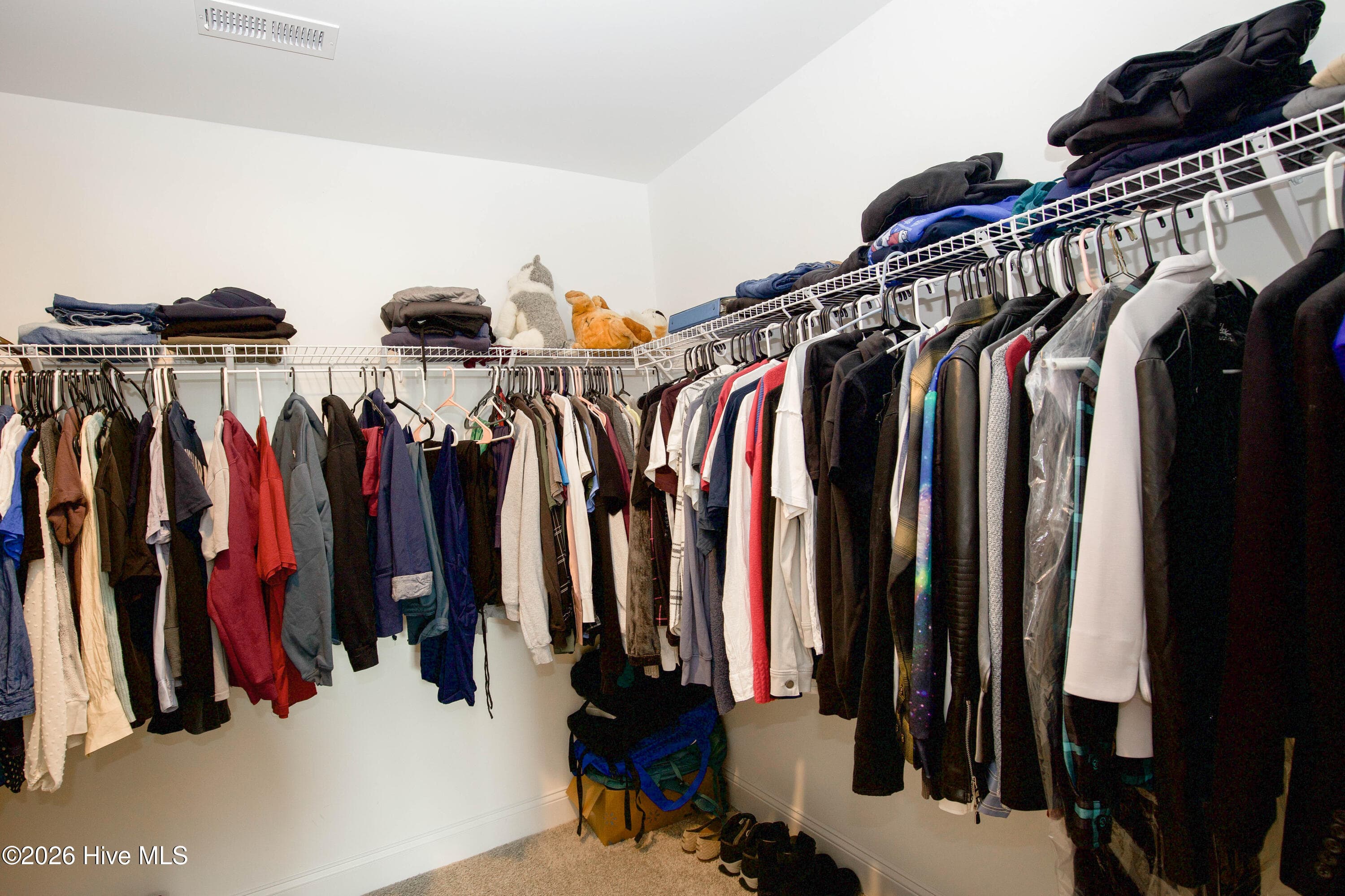 The primary walk-in closet has wire shelving with hanging rods on two walls and floor space for shoes and storage bins. It gives you room for a full wardrobe plus seasonal items. According to the floor plan, the closet measures approximately 9'9" by 8'2". - 221 Vega Lane, Linden, NC 28356