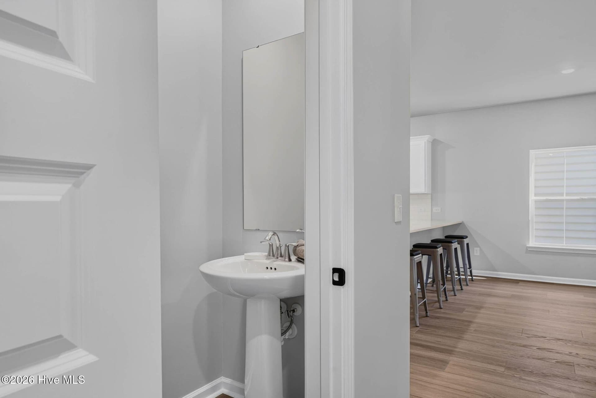 Convenient main-level half bathroom featuring a pedestal sink, modern fixtures, and easy access from the main living areas. - 3447 Sandhill Crane Drive SW, Ocean Isle Beach, NC 28469