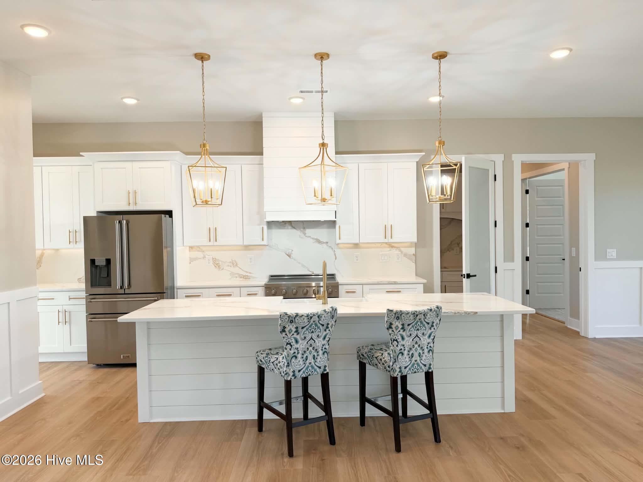 Looking at kitchen from open concept great room. Custom lighting, counter tops, backsplash, faucet and cabinet hardware. - 550 Glenburnie Street NW, Calabash, NC 28467