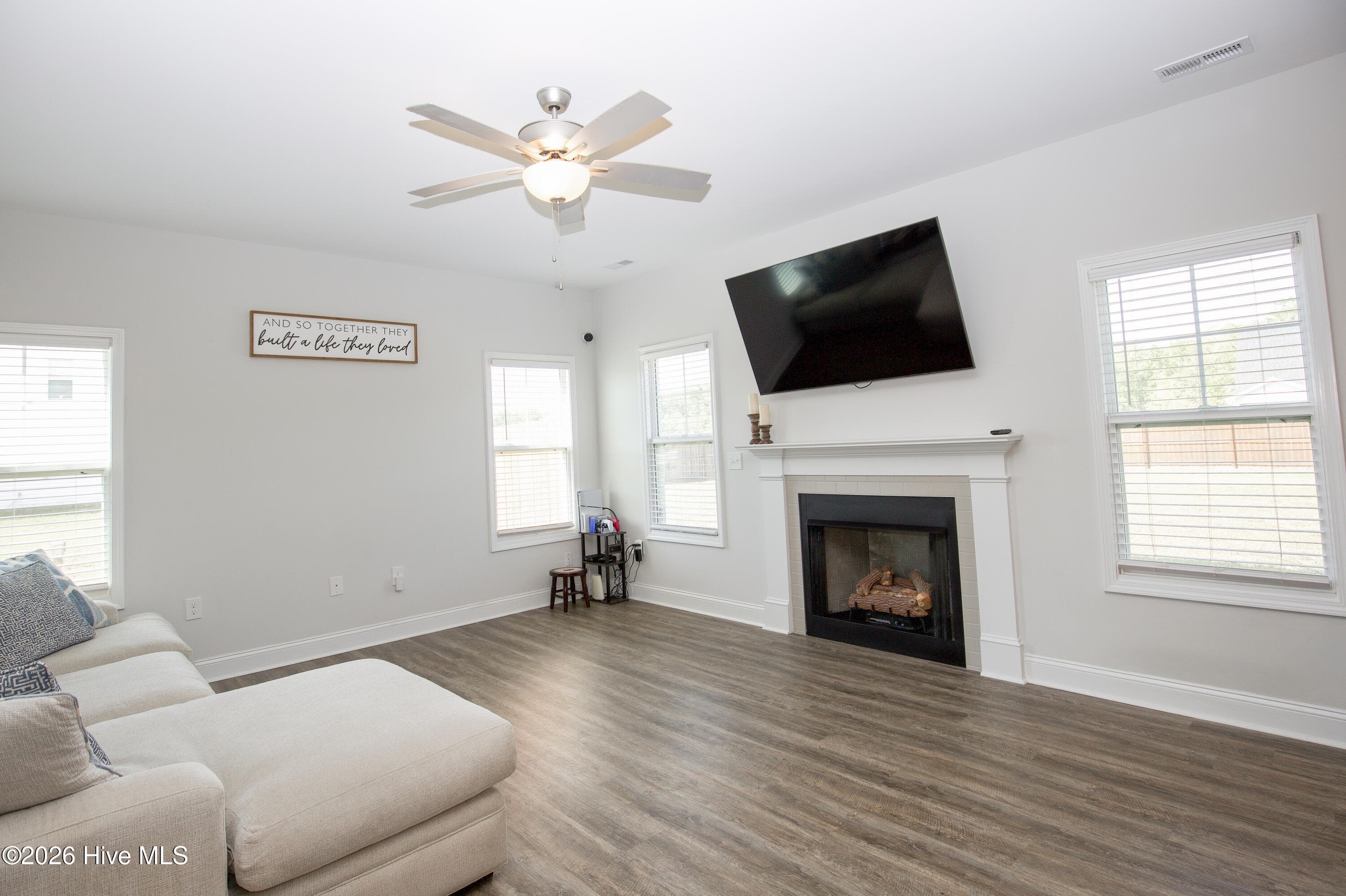 This angle of the Great Room shows the fireplace as the natural focal point, with room for a large sectional and additional seating around it. Windows on three sides bring in natural light throughout the day. The wall space above the mantel and around the room gives you flexibility in how you arrange furniture and a television. - 221 Vega Lane, Linden, NC 28356