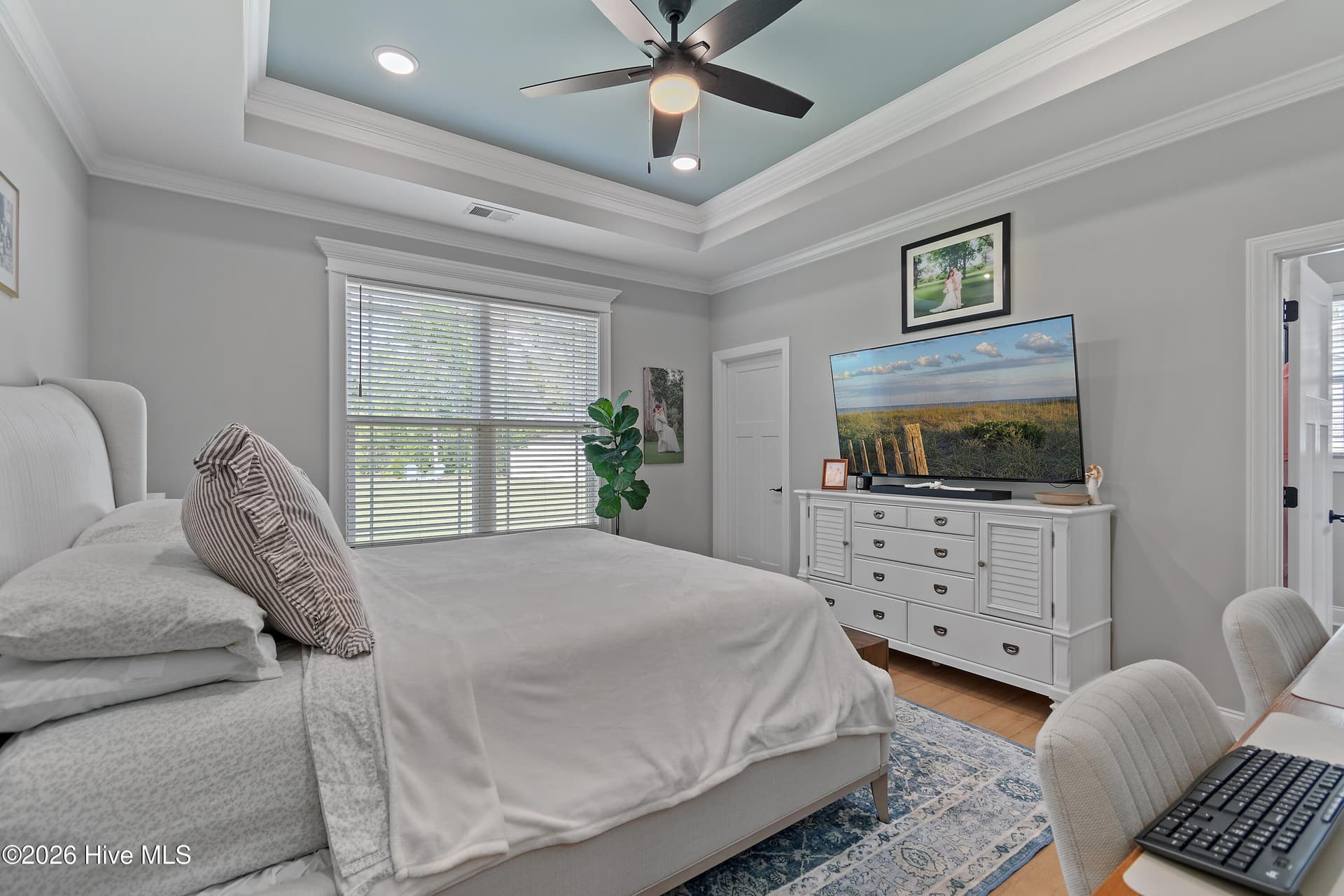 Primary bedroom with an en suite bathroom, luxury trim, tray ceiling, and ceiling fan. - 299 Boundaryline Drive NW, Calabash, NC 28467