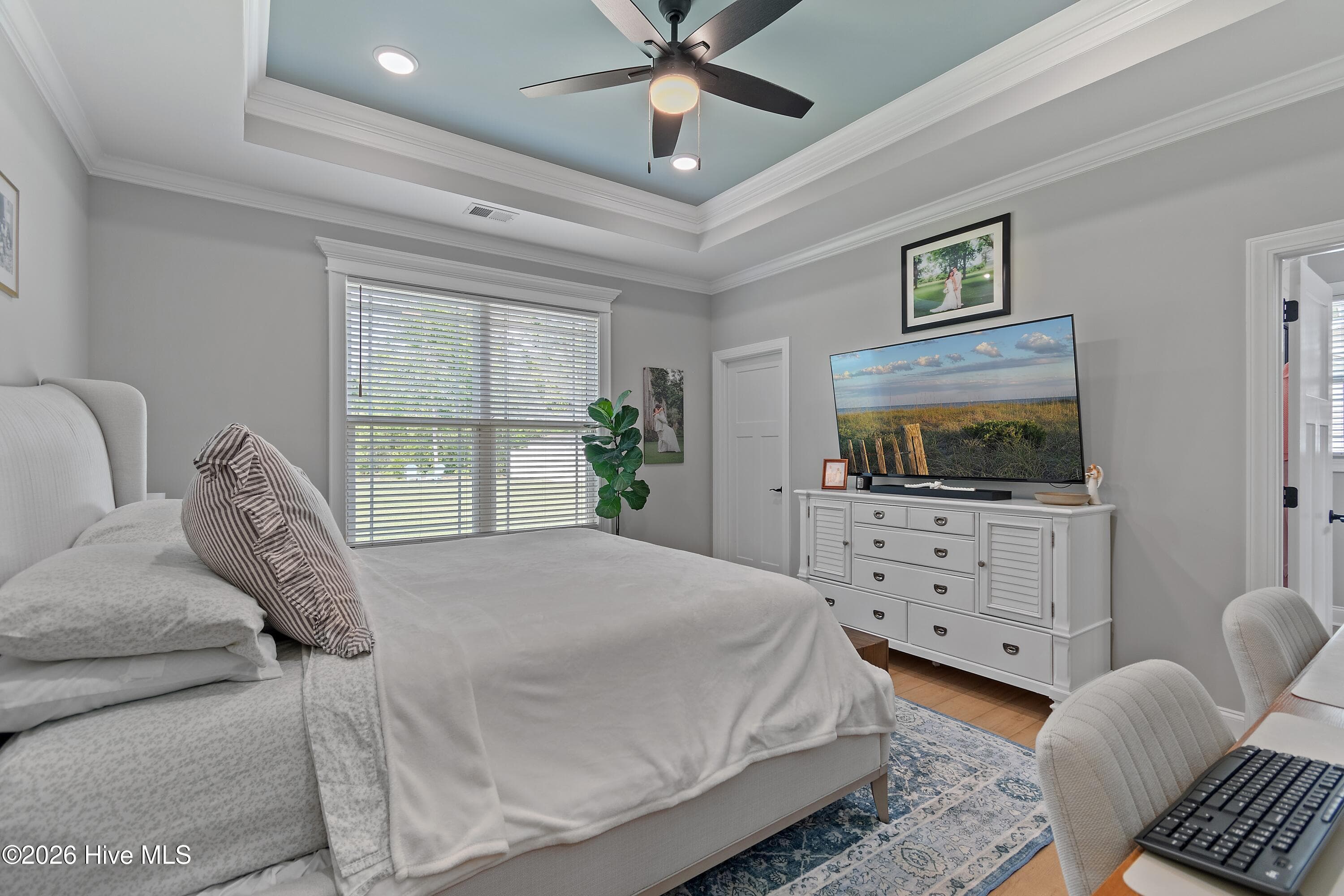 Primary bedroom with an en suite bathroom, luxury trim, tray ceiling, and ceiling fan. - 299 Boundaryline Drive NW, Calabash, NC 28467