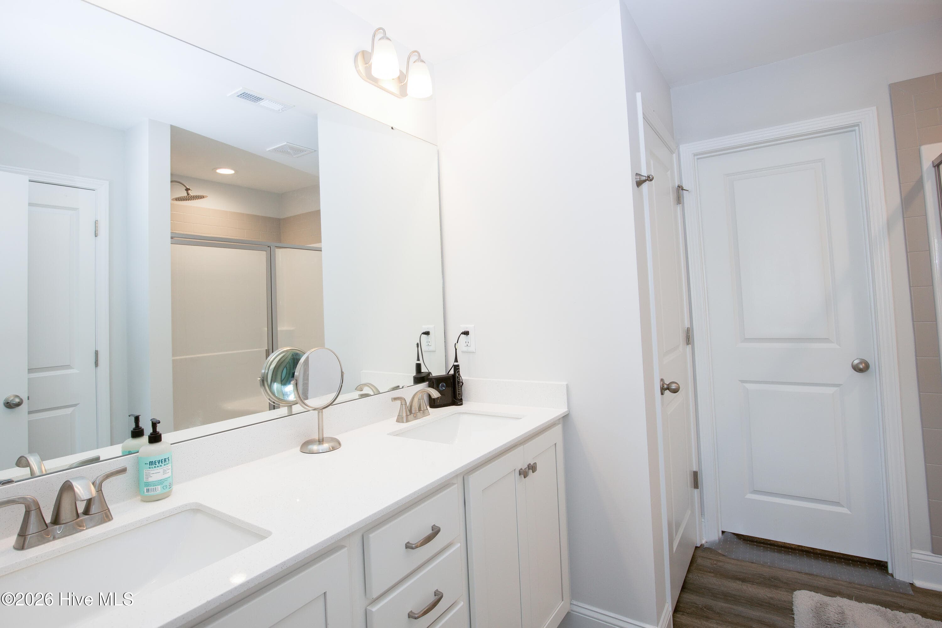 The primary bath includes a double vanity with two sinks, a large mirror, and cabinets and drawers below. Two sinks give each person their own space to get ready in the morning. The primary bath also includes a separate toilet room for added privacy. - 221 Vega Lane, Linden, NC 28356