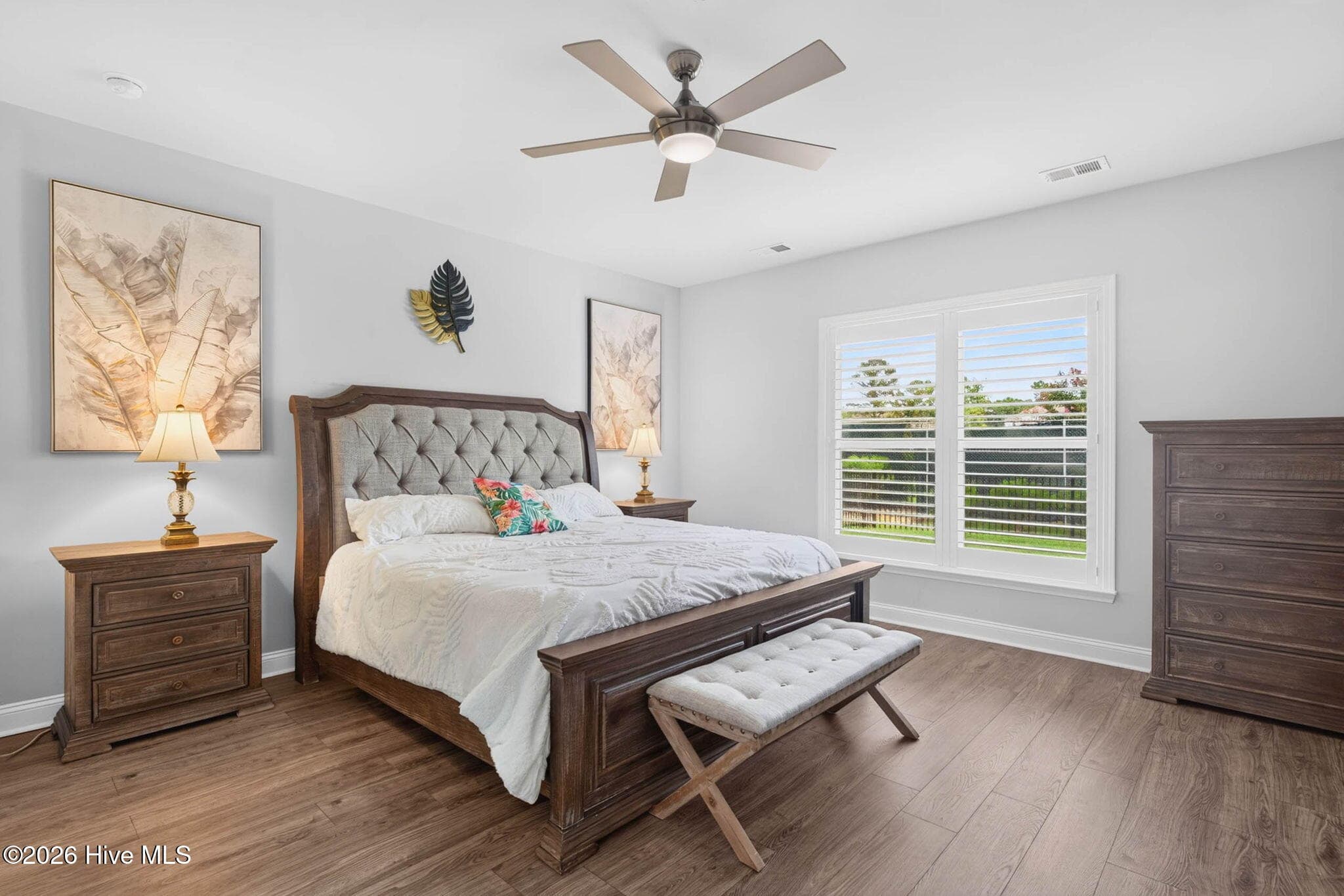The main-level primary suite offers a spacious retreat with a tray ceiling, ceiling fan, and abundant natural light. - 139 Eagle Claw Drive, Calabash, NC 28467