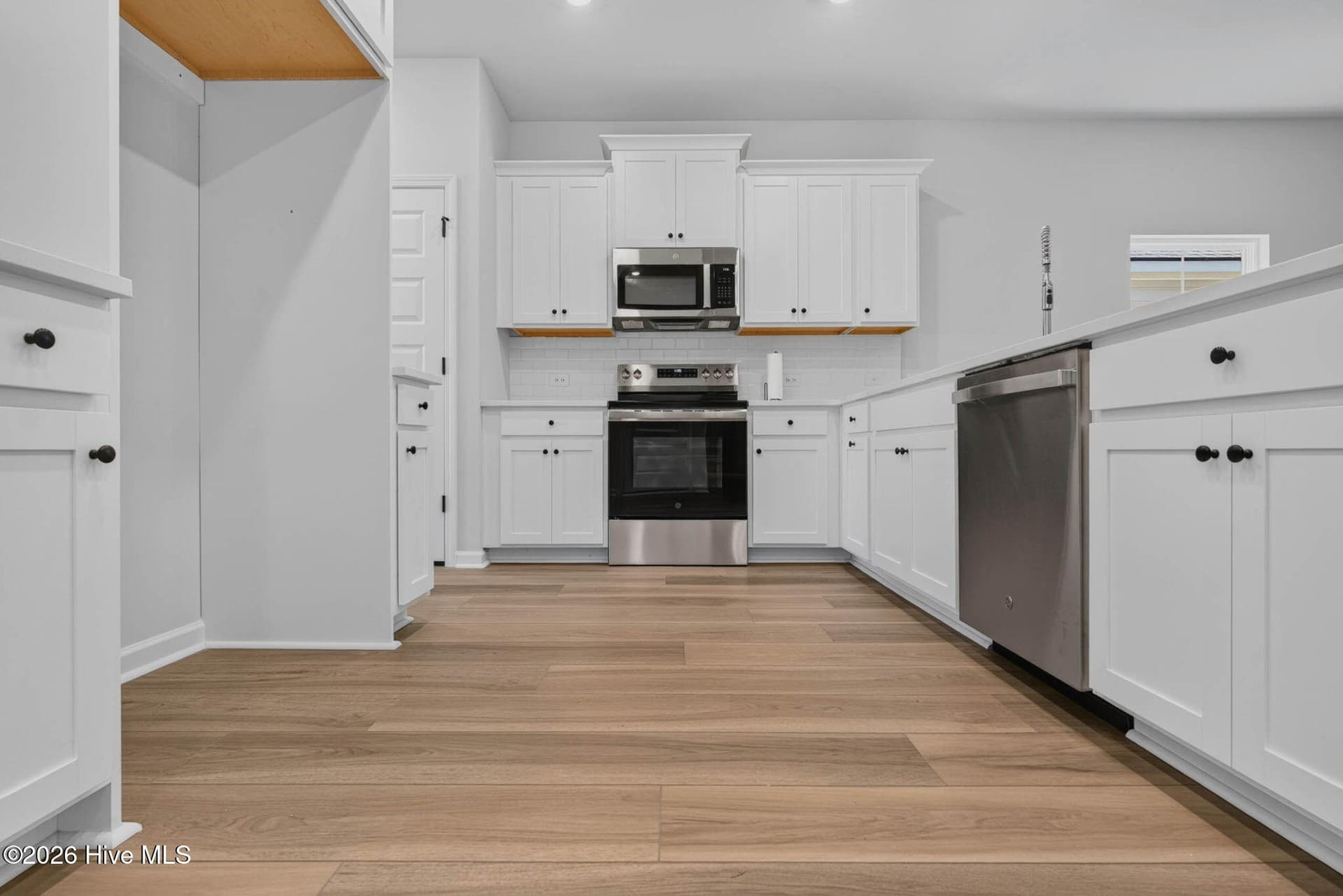 Modern kitchen showcasing stainless steel appliances, generous counter space, and luxury vinyl plank flooring. - 3447 Sandhill Crane Drive SW, Ocean Isle Beach, NC 28469
