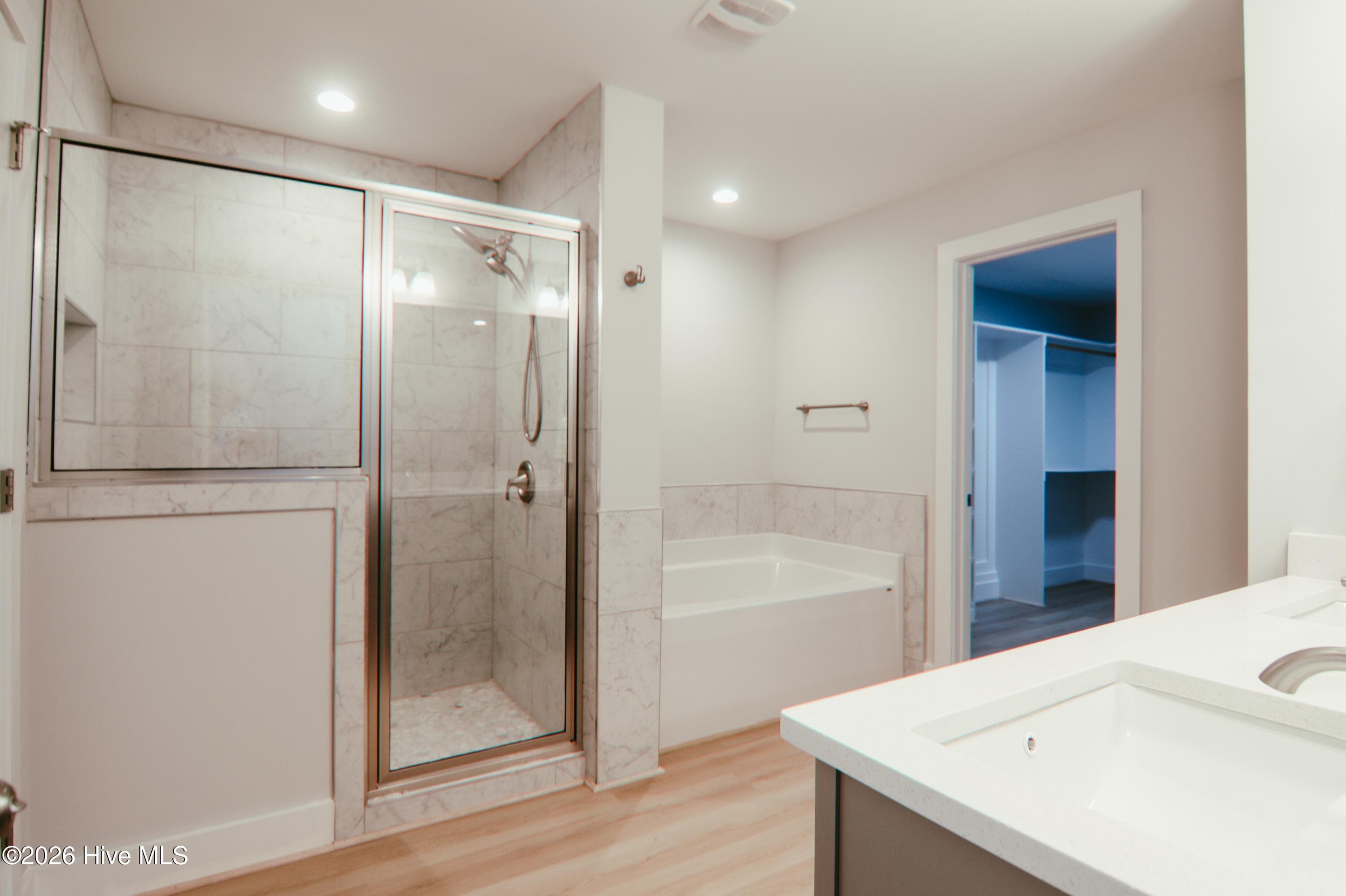 The spa-inspired en-suite bathroom includes a tiled walk-in shower, soaking tub with tile surround - 223 Glenwood Trail, Goldsboro, NC 27534